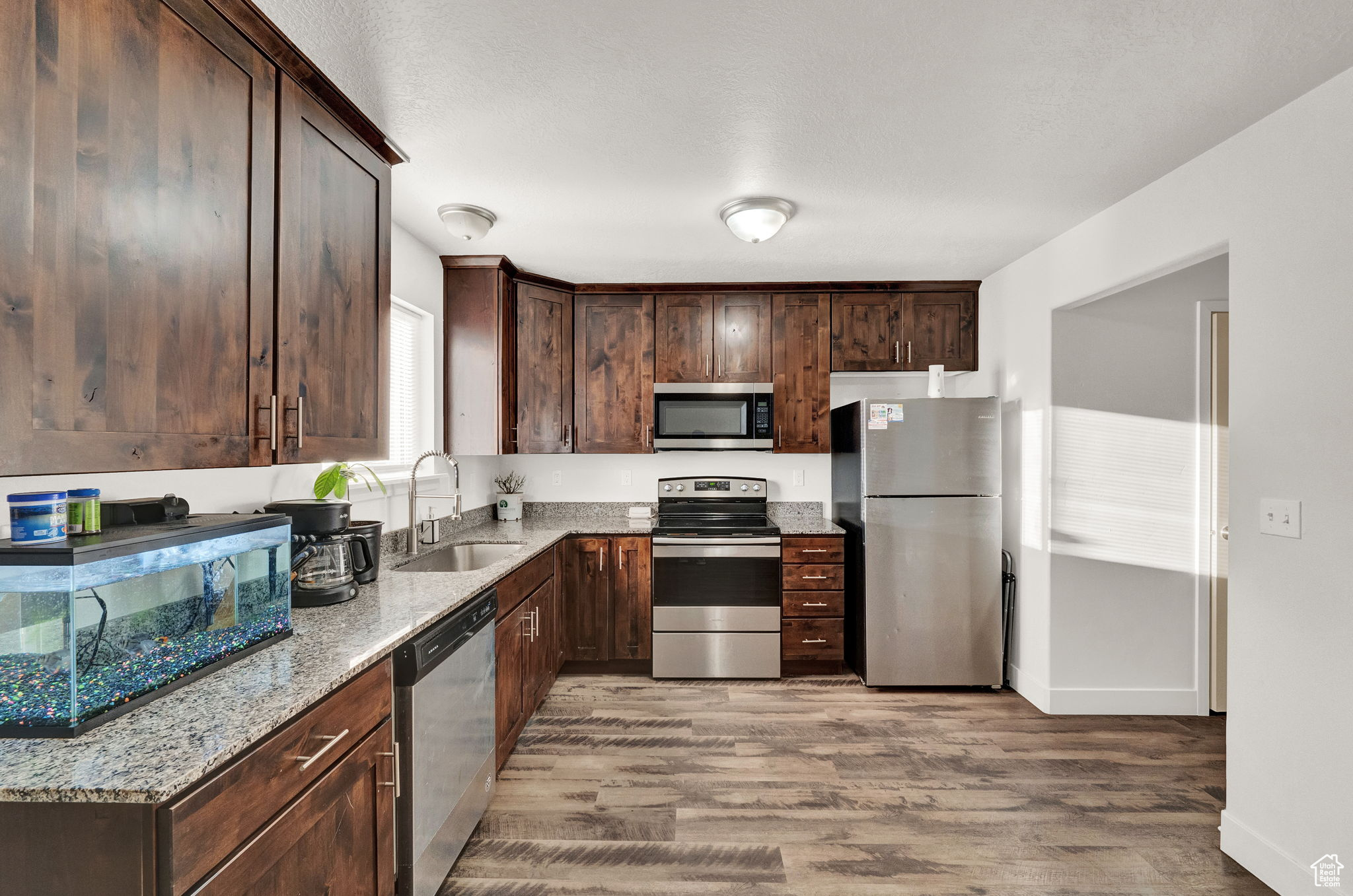 Kitchen featuring light stone counters, stainless steel appliances, light hardwood / wood-style flooring, and sink