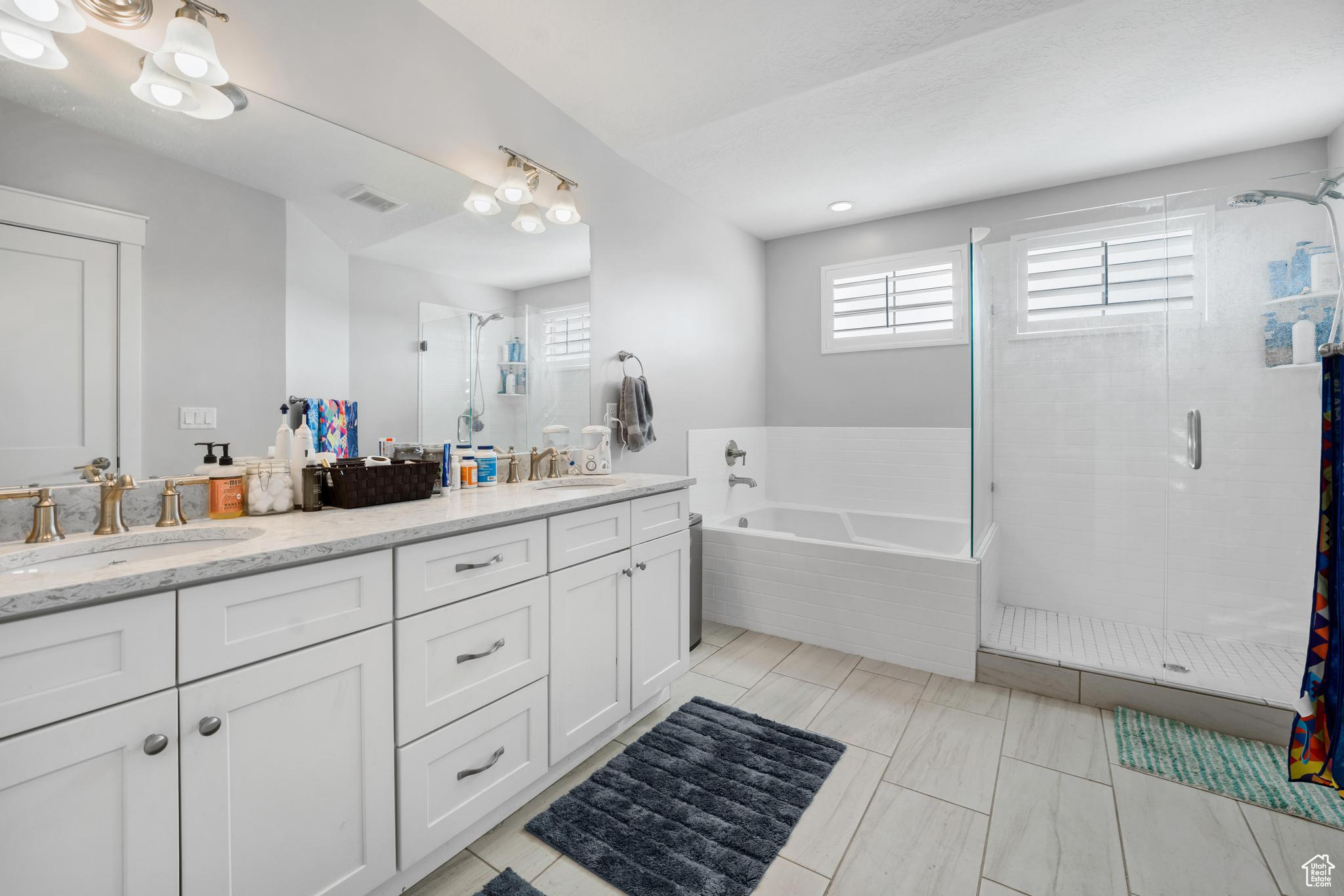 Bathroom featuring shower with separate bathtub, large vanity, double sink, and tile flooring