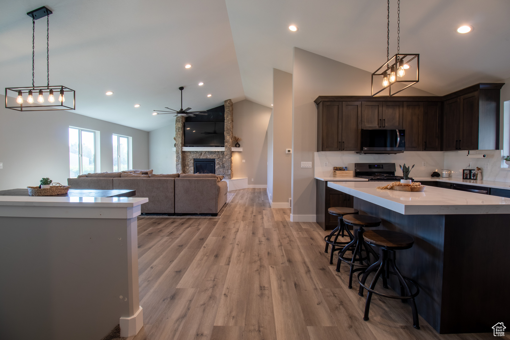 Kitchen featuring a fireplace, backsplash, light hardwood / wood-style floors, range, and vaulted ceiling
