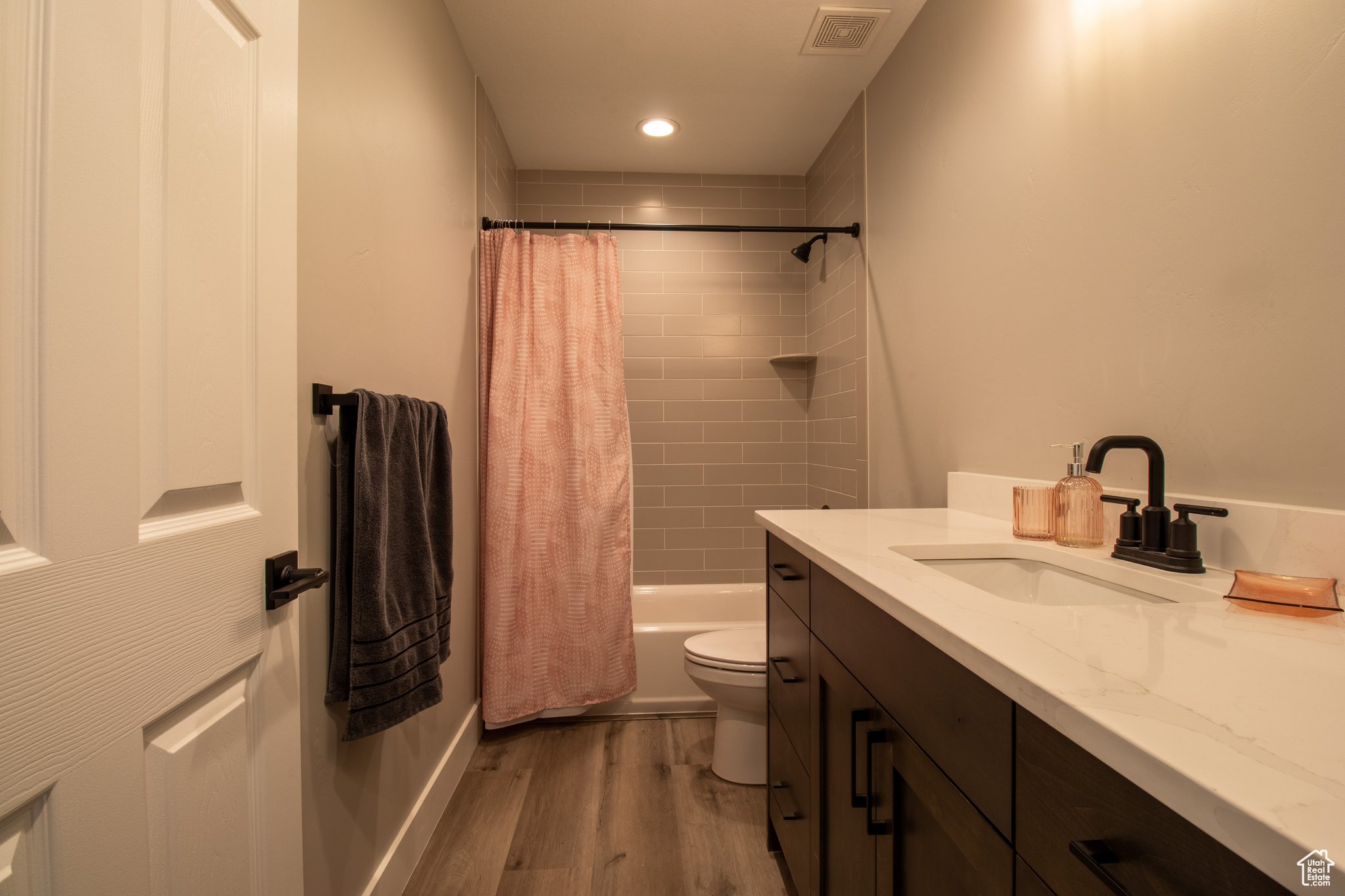 Full bathroom featuring hardwood / wood-style flooring, vanity, shower / bath combo, and toilet