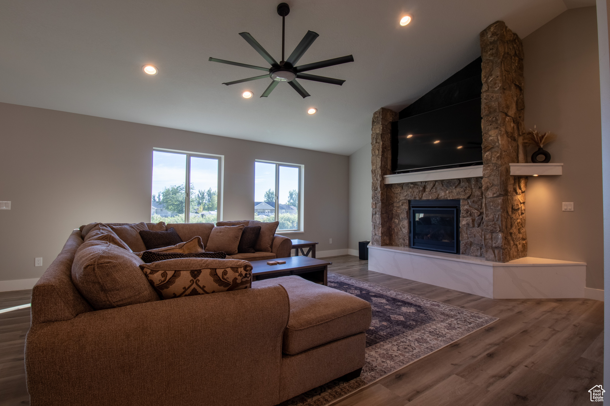 Living room with a fireplace, dark hardwood / wood-style flooring, high vaulted ceiling, and ceiling fan