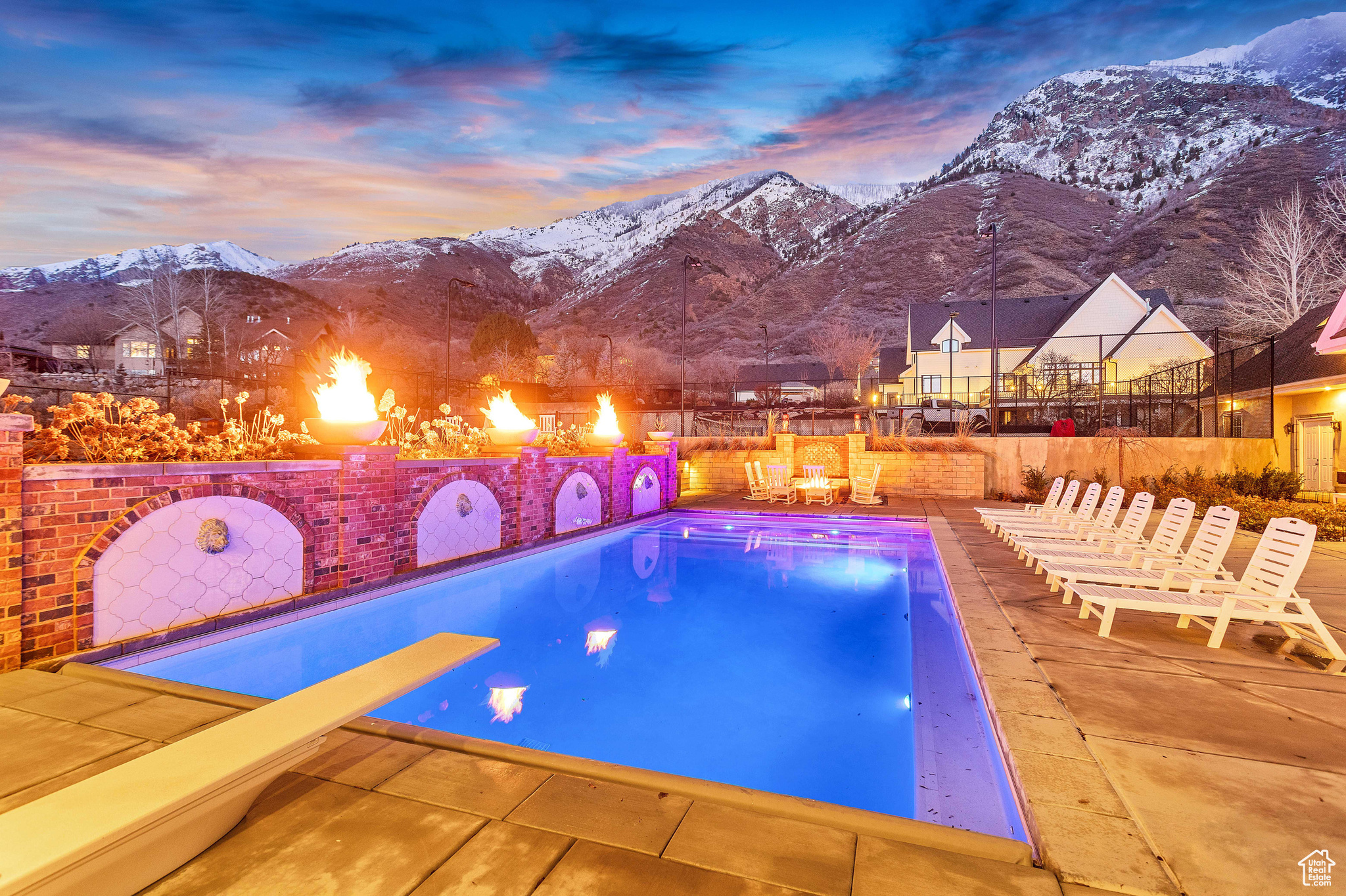 Pool at dusk with a mountain view, a patio, and a diving board