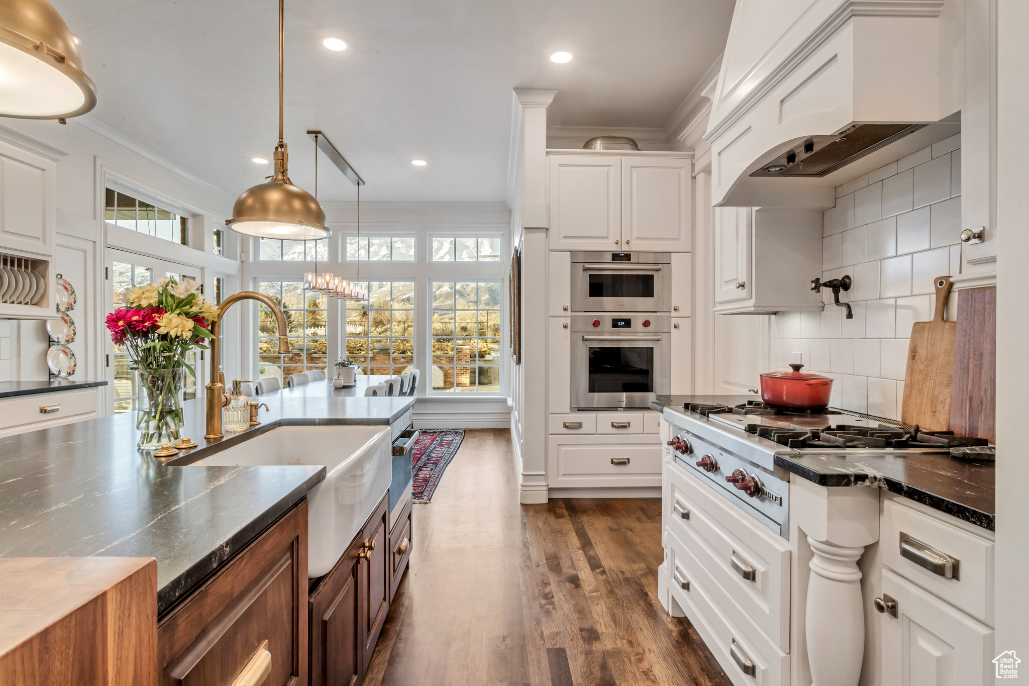 Kitchen with hanging light fixtures, tasteful backsplash, a healthy amount of sunlight, and white cabinets