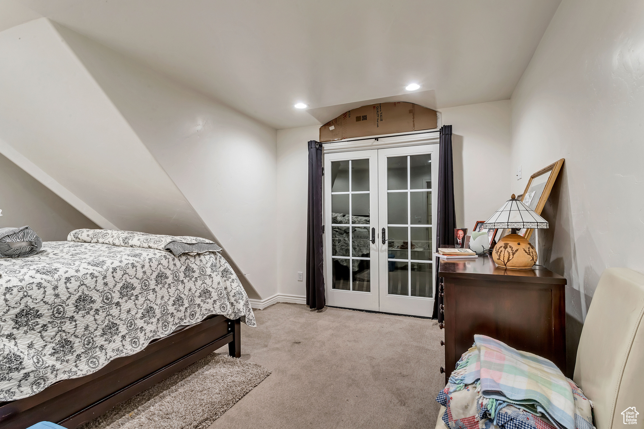 Carpeted bedroom with lofted ceiling and french doors