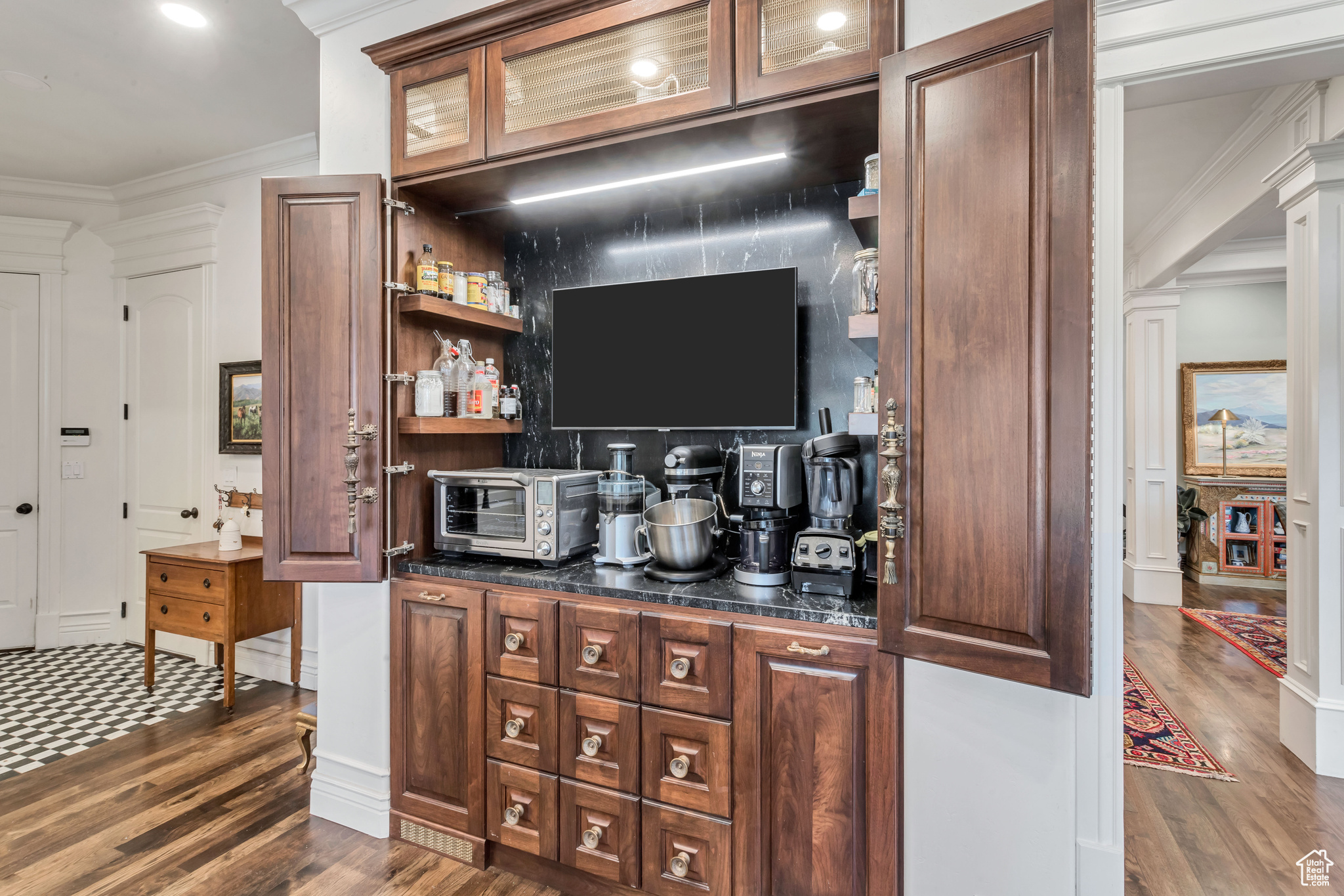 Bar featuring dark hardwood/wood flooring, dark brown cabinets, and ornamental molding