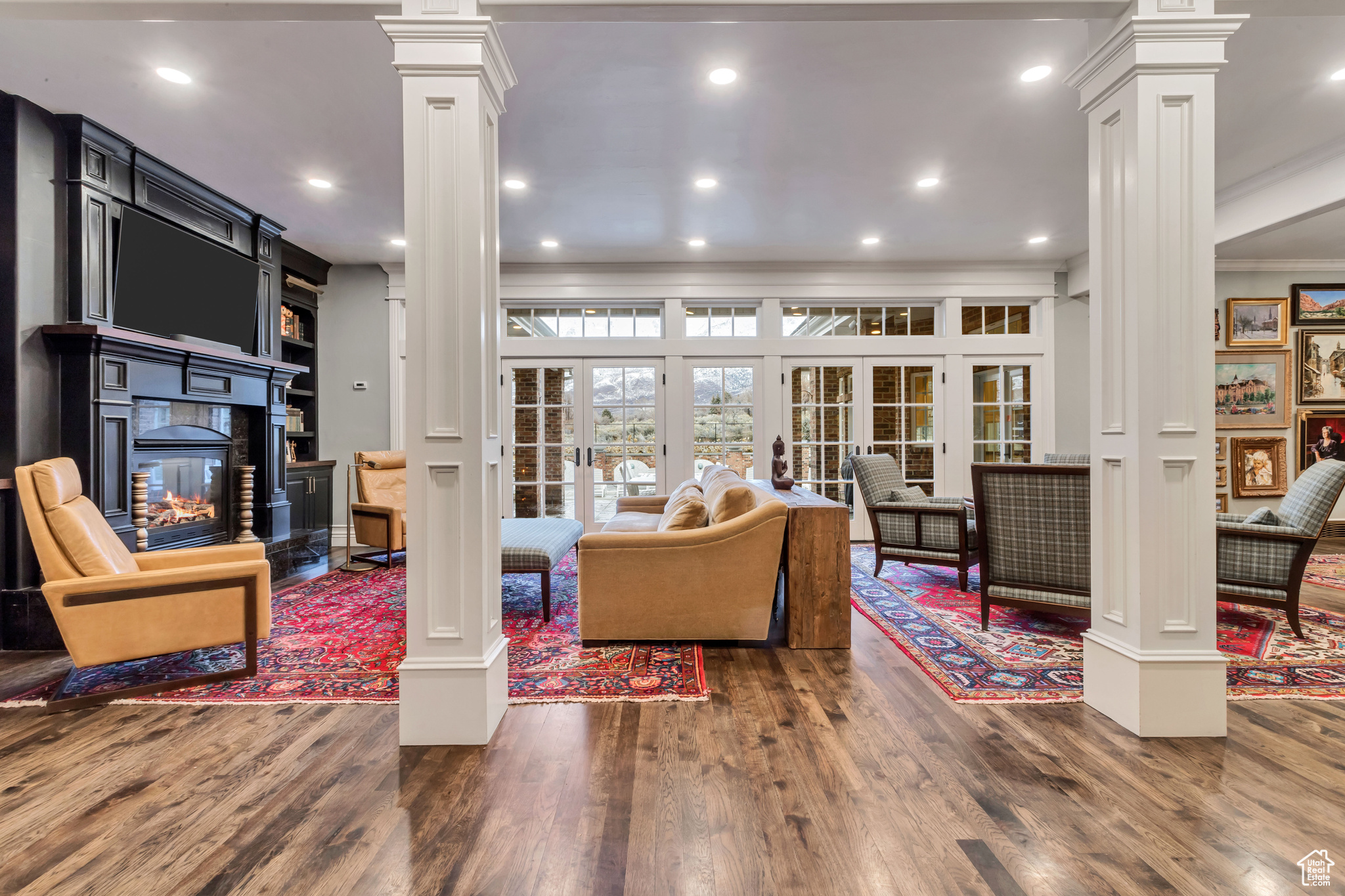 Living room with dark hardwood / wood floors, ornamental molding, ornate columns, and french doors