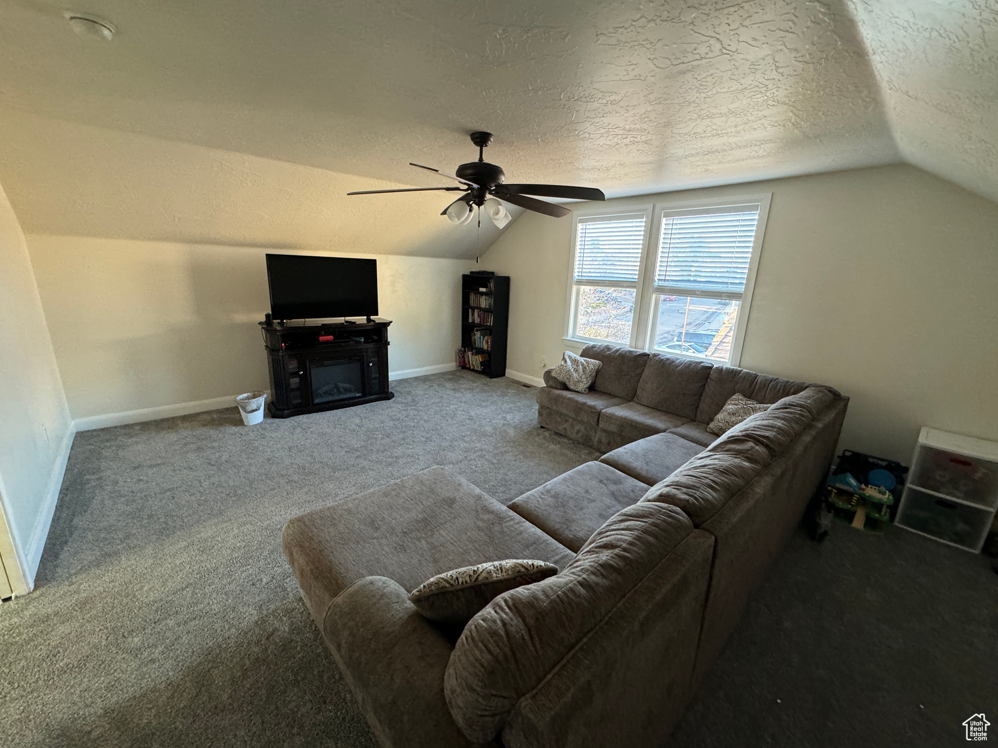 Living room with ceiling fan, a textured ceiling, and carpet