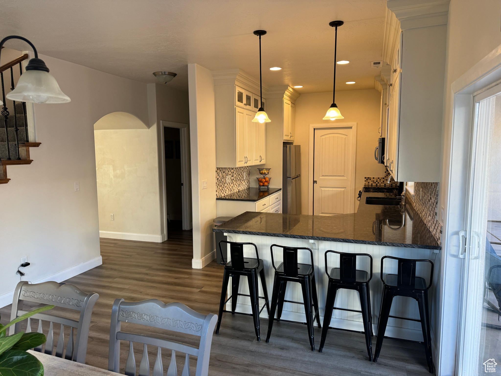 Kitchen featuring pendant lighting, dark hardwood / wood-style flooring, stainless steel appliances, backsplash, and kitchen peninsula