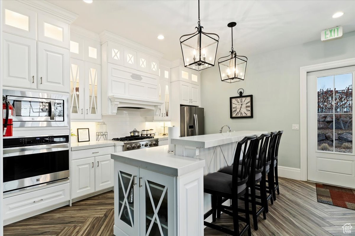 Kitchen with white cabinetry, a kitchen island, a breakfast bar, appliances with stainless steel finishes