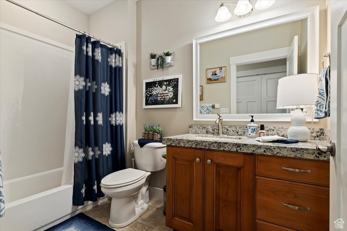 Full bathroom with vanity, toilet, shower / tub combo with curtain, and tile floors