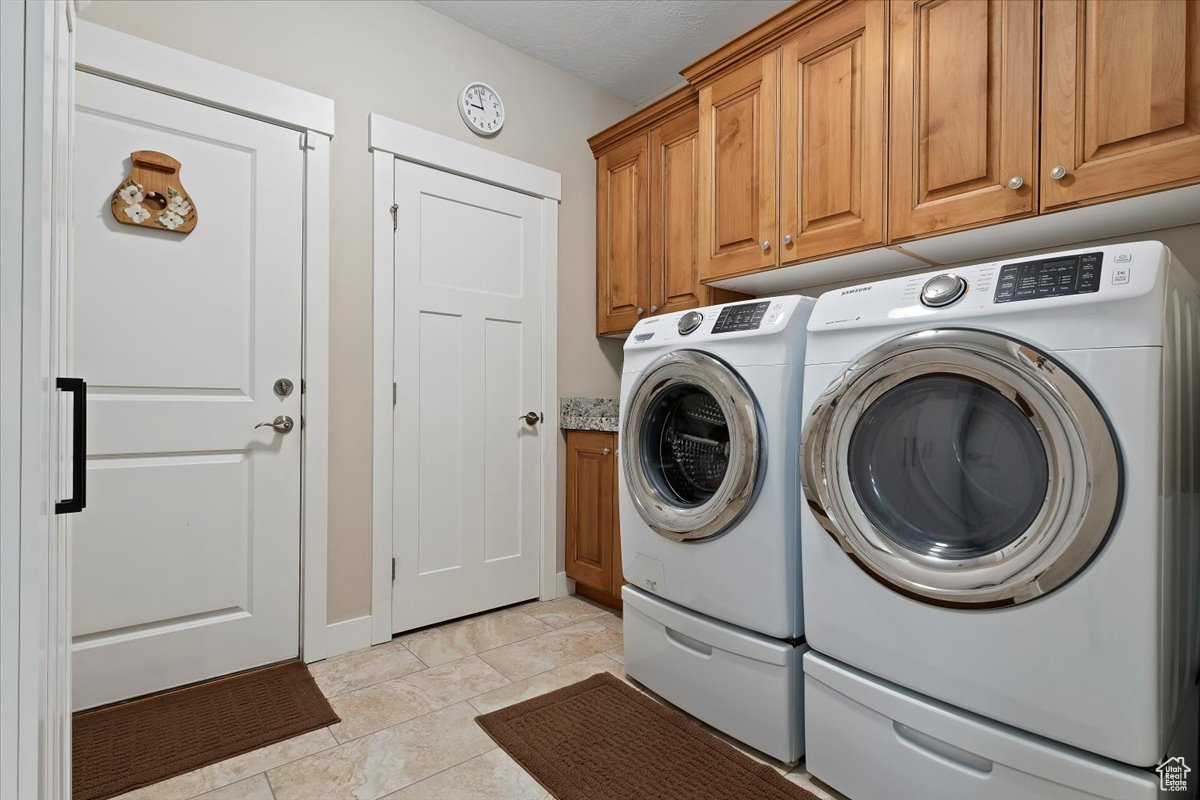 Washroom featuring light tile flooring, independent washer and dryer, and cabinets