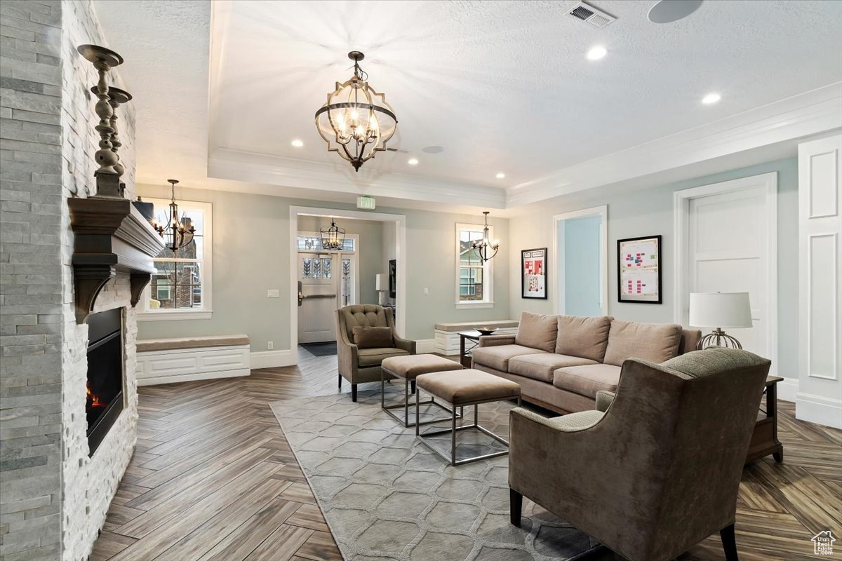 Living room featuring brick wall, a notable chandelier, a raised ceiling