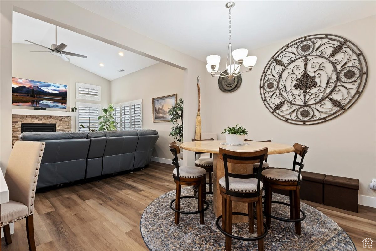 Dining room featuring a stone fireplace, vaulted ceiling