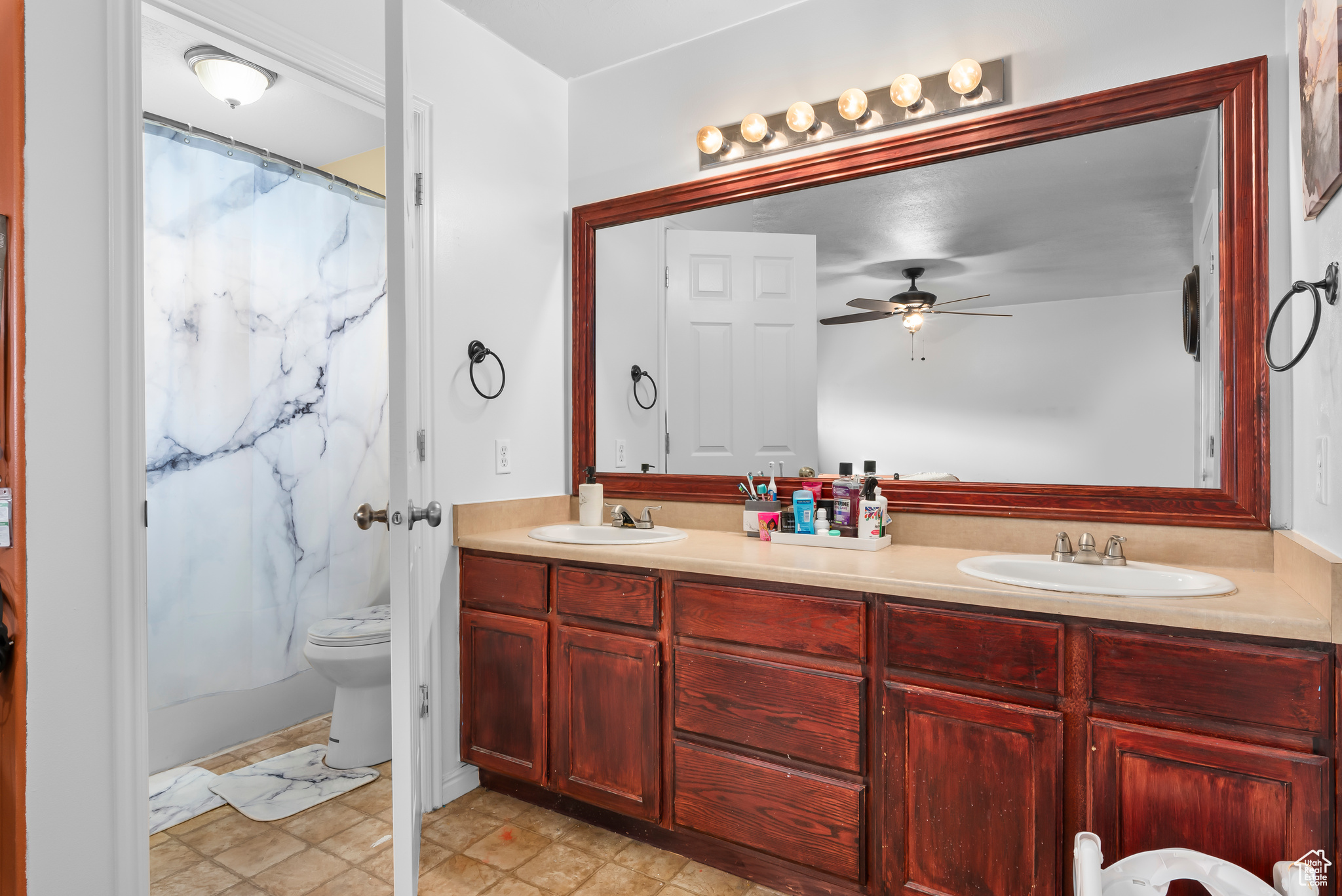 Master Bathroom featuring ceiling fan, oversized vanity, toilet, and double sink