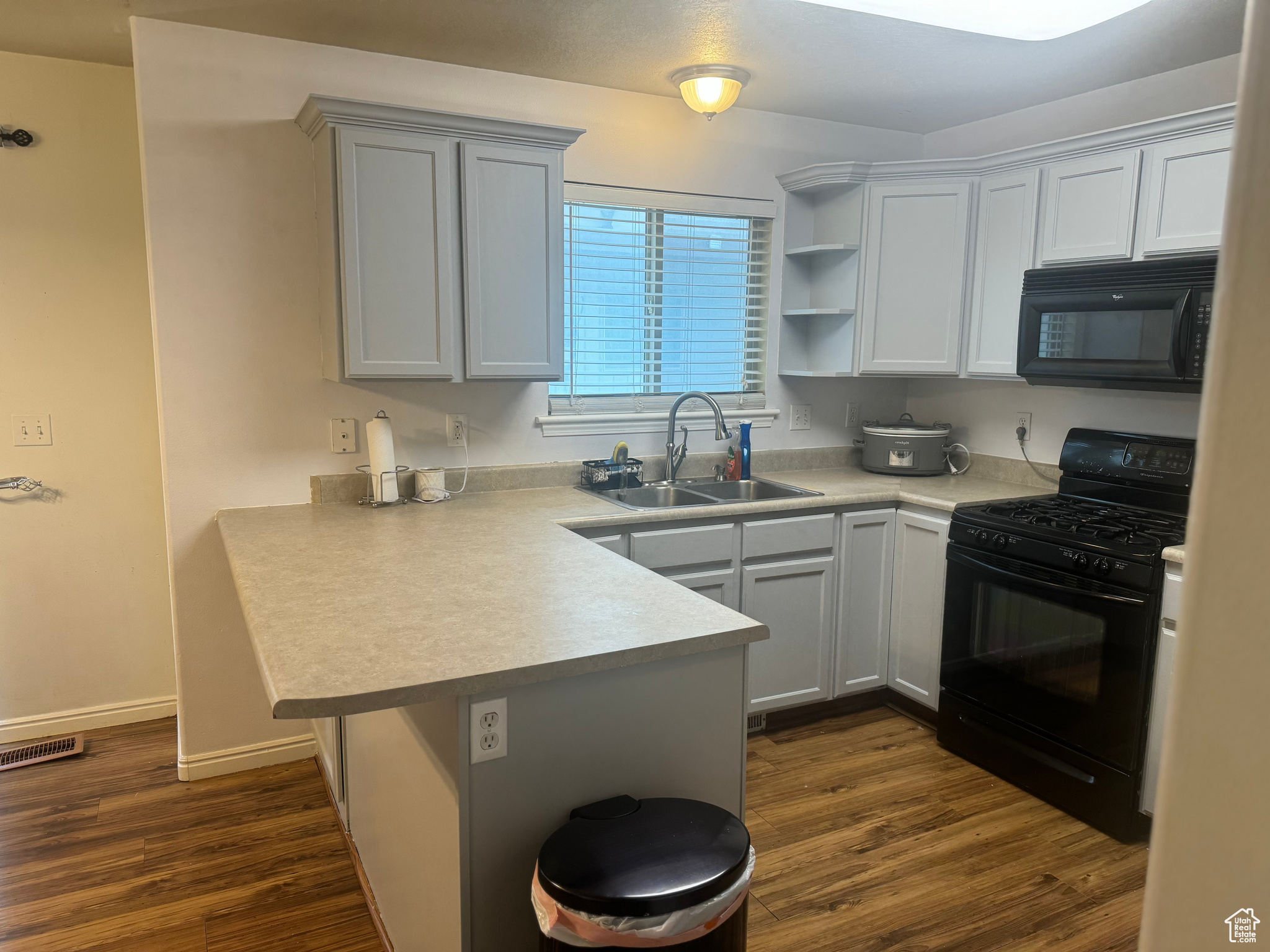 Kitchen featuring sink, black appliances, LVP wood-style floors, and light grey cabinetry