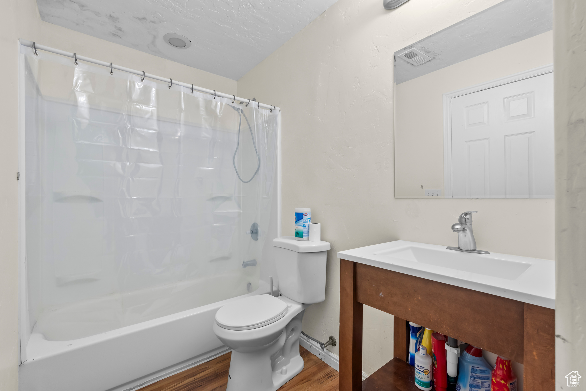 Full bathroom with vanity, toilet, shower / tub combo, and hardwood / wood-style floors