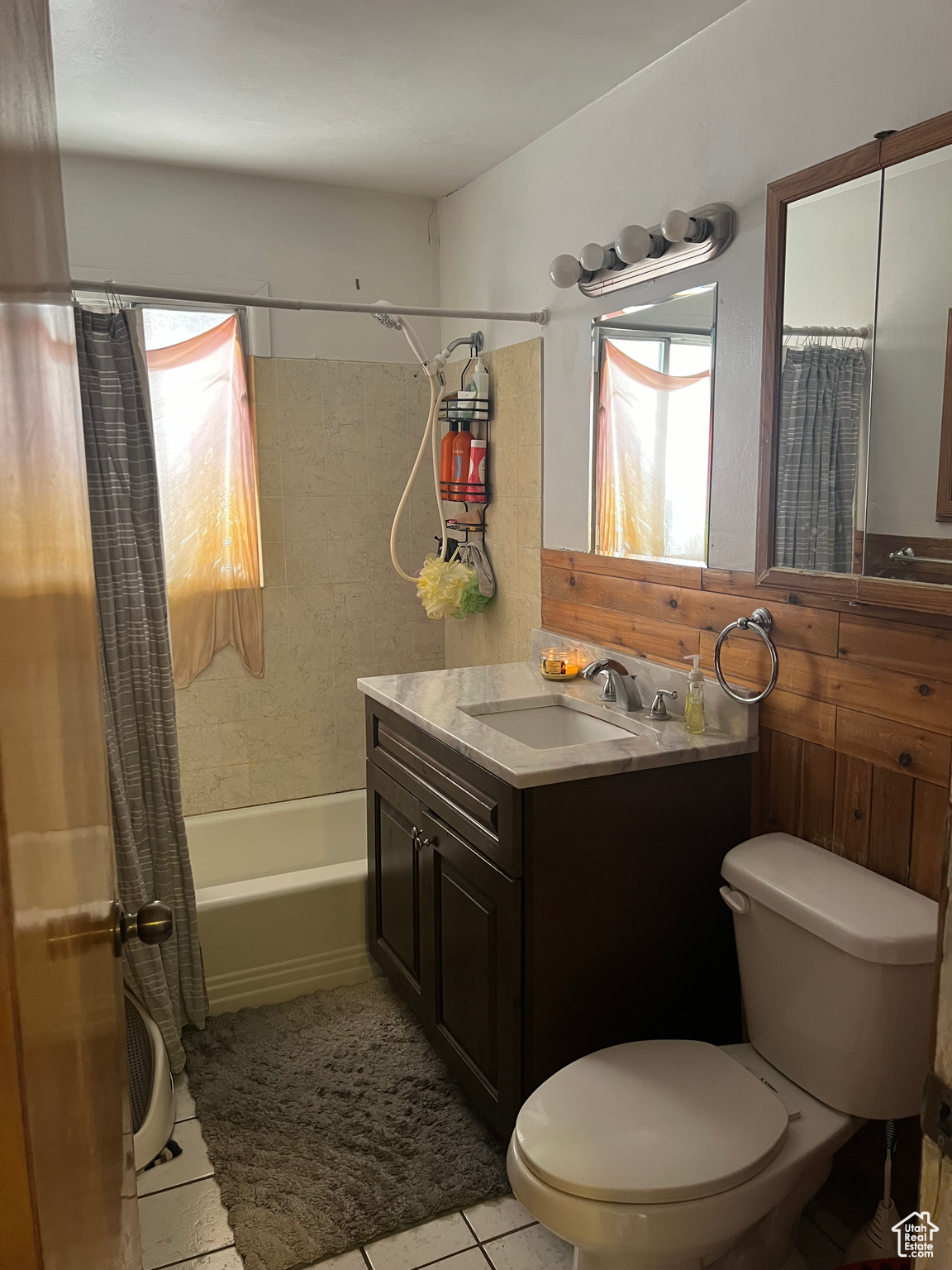 Full bathroom featuring tile floors, large vanity, toilet, and shower / tub combo with curtain