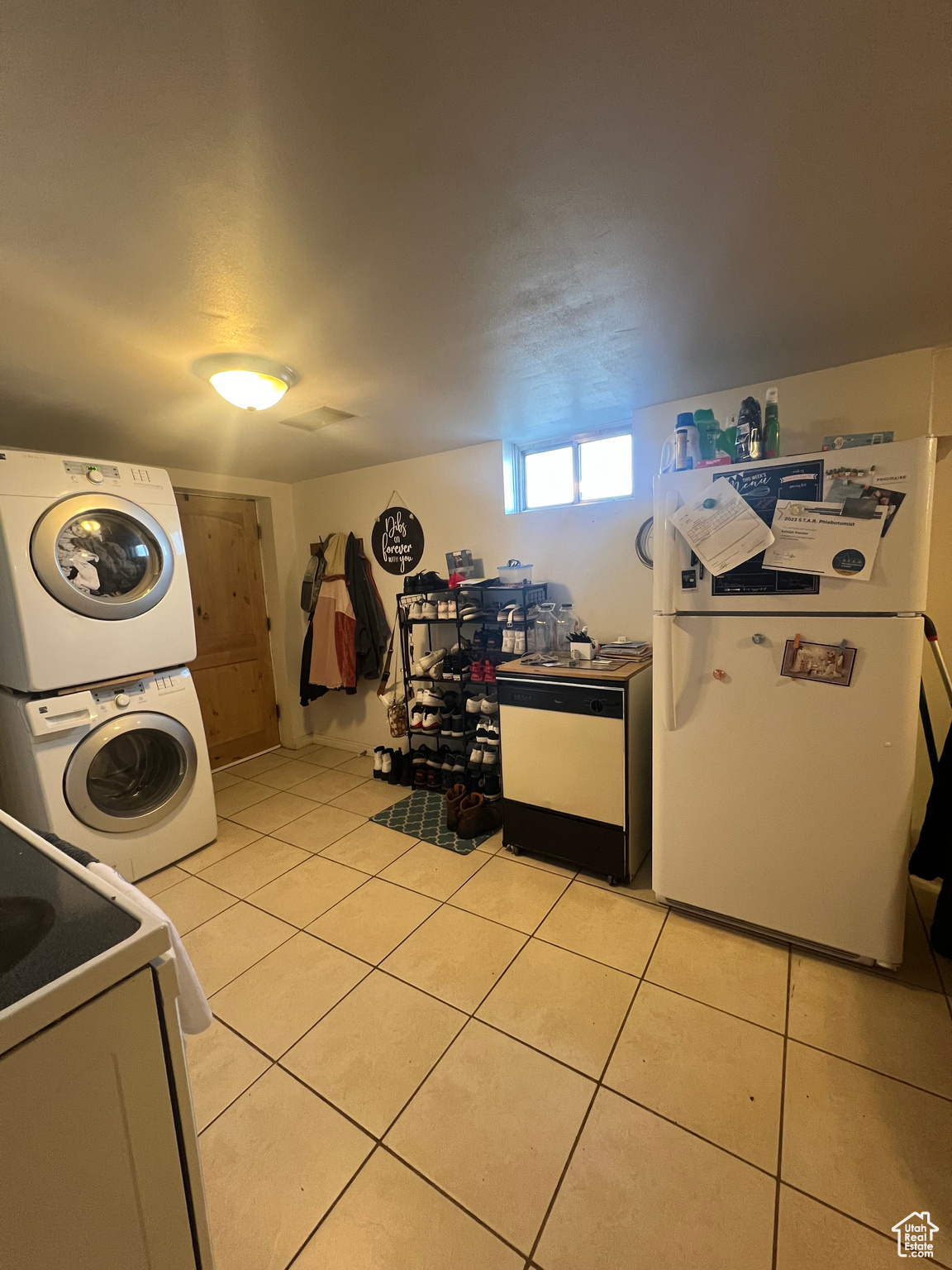 Kitchen featuring white appliances, light tile floors, and stacked washer and dryer