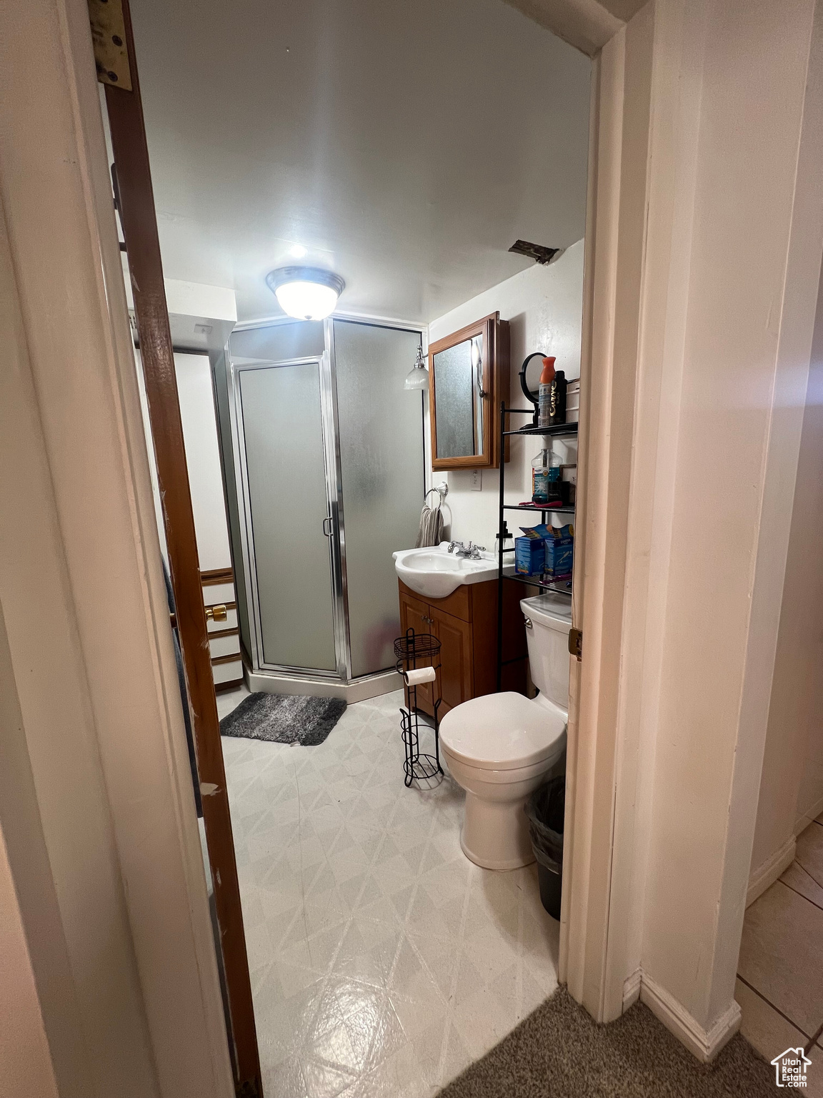 Bathroom featuring vanity, toilet, tile flooring, and an enclosed shower