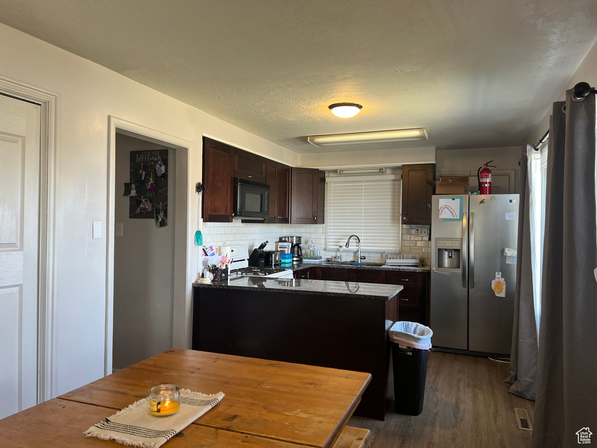 Kitchen with stainless steel fridge with ice dispenser, tasteful backsplash, and dark brown cabinetry