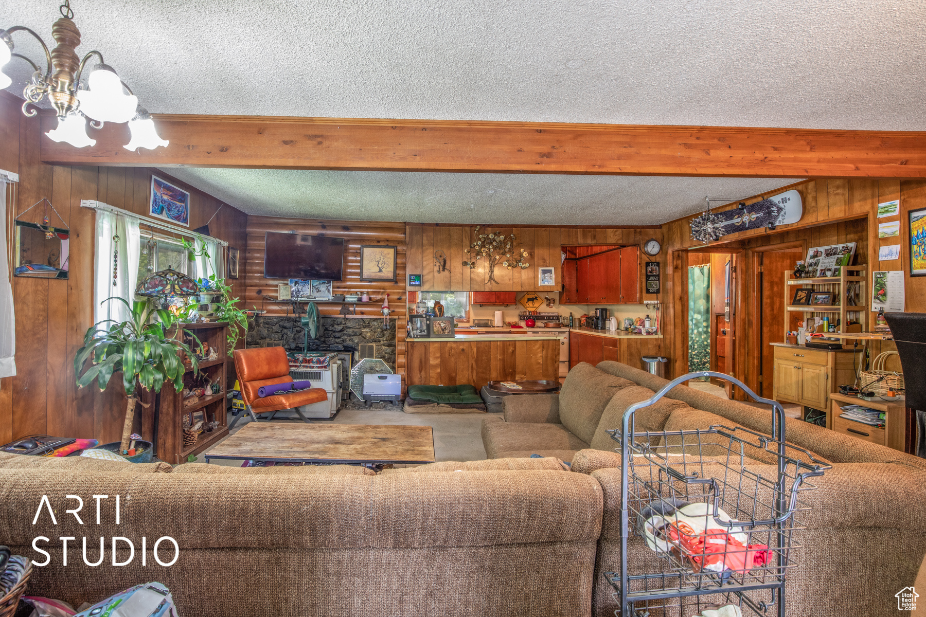 Carpeted living room featuring beam ceiling, wood walls,