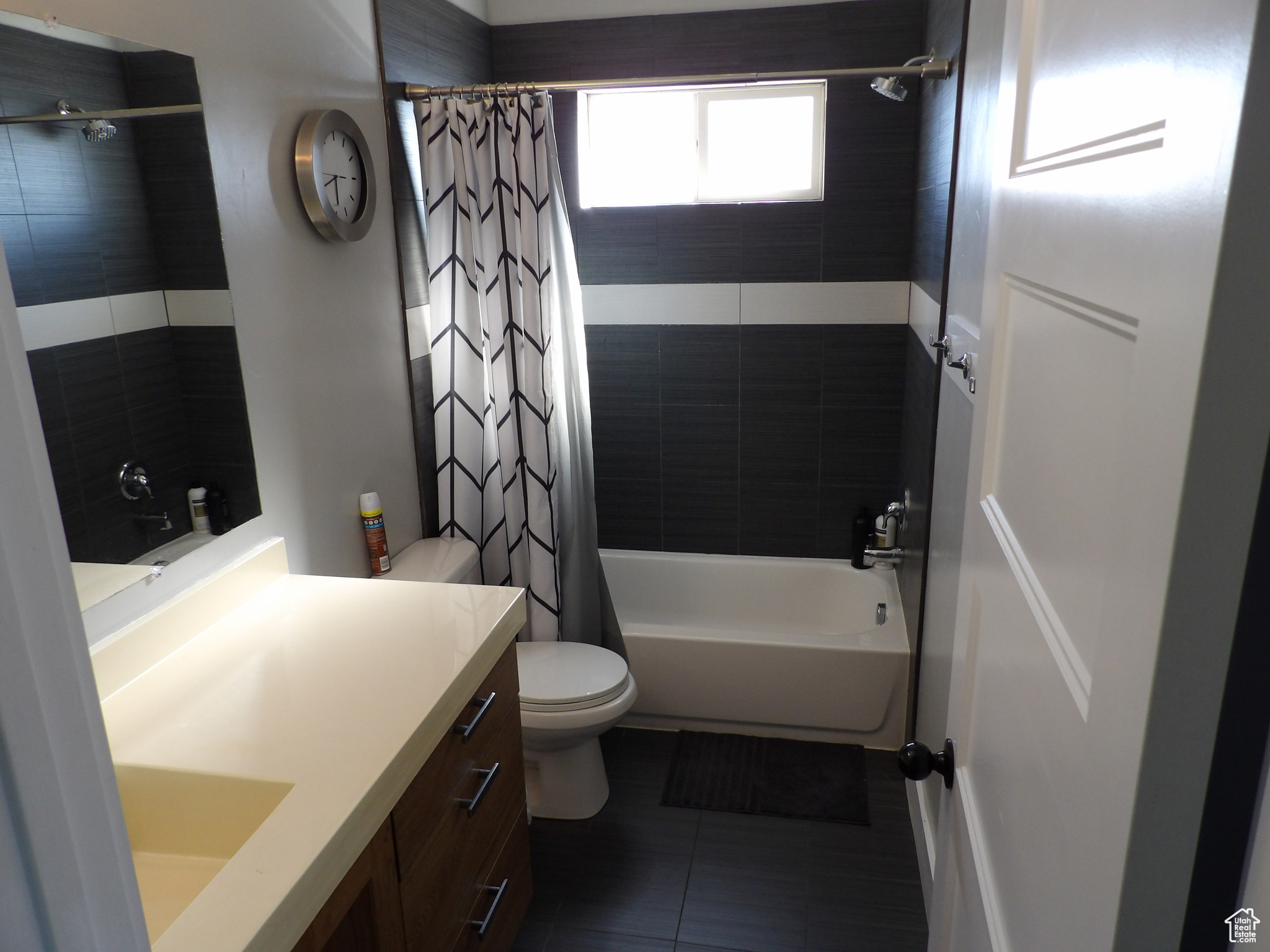 Full bathroom featuring tile flooring, large vanity, shower / tub combo with curtain, and toilet