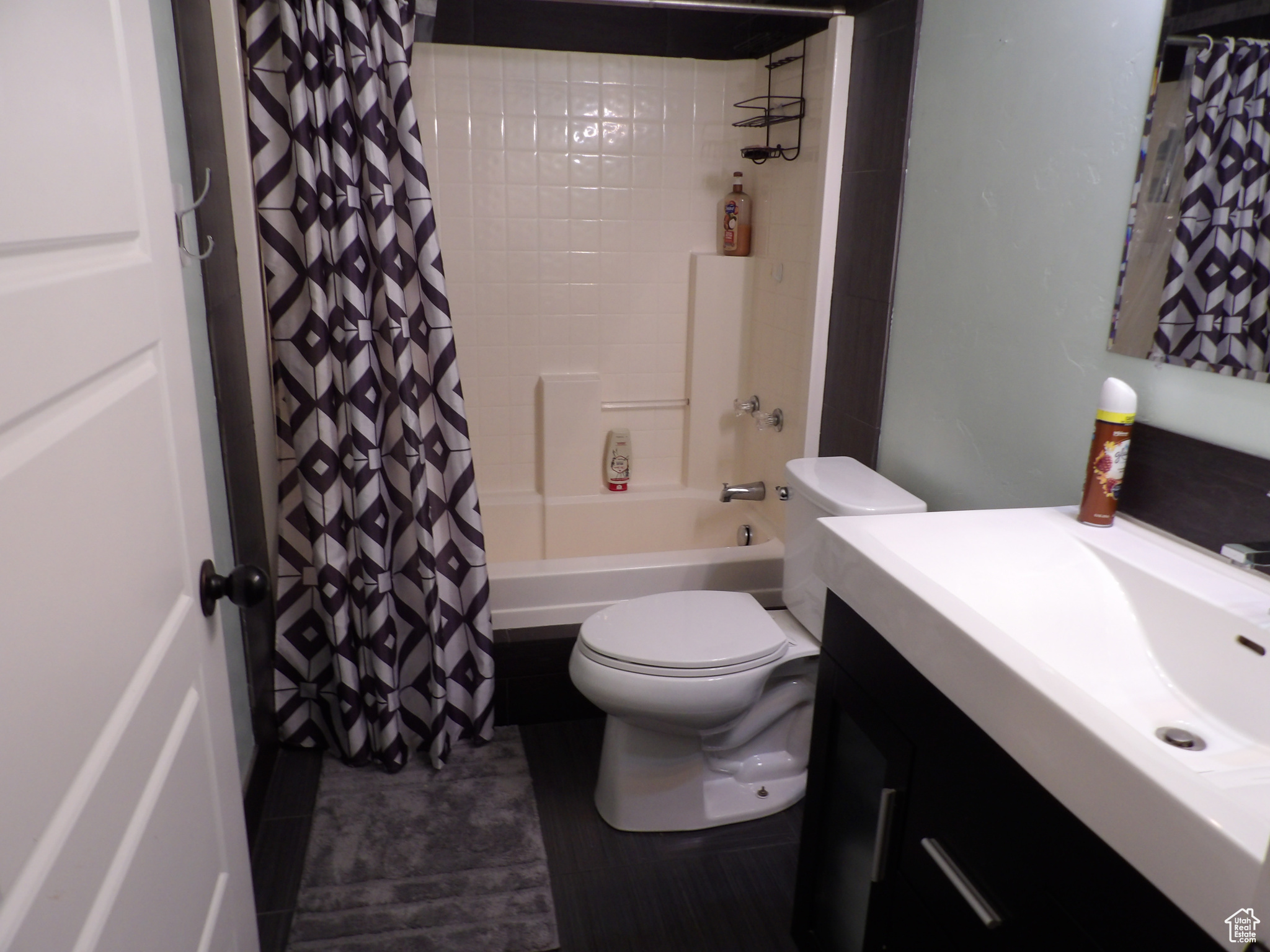 Full bathroom featuring large vanity, toilet, and shower / bath combination with curtain