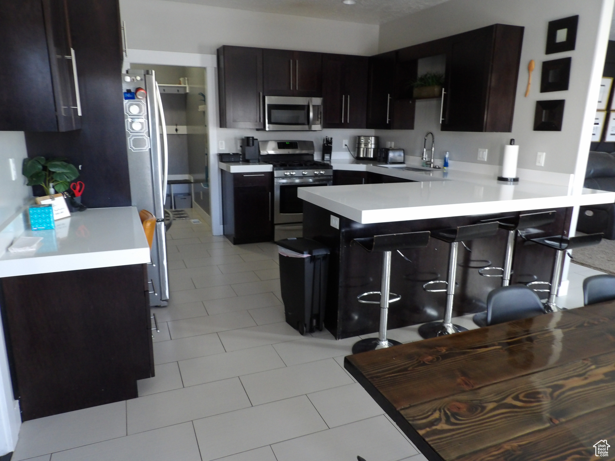 Kitchen featuring a breakfast bar area, stainless steel appliances, sink, light tile floors, and kitchen peninsula