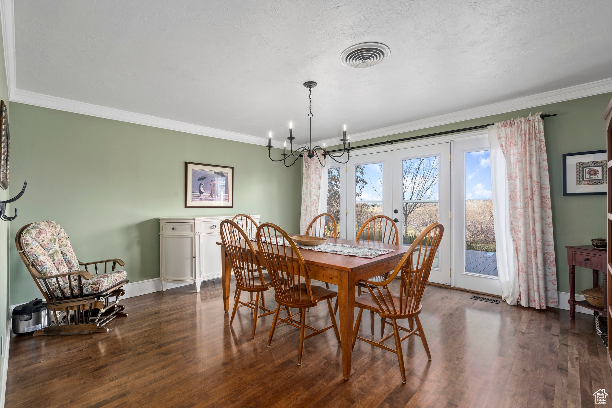 Dining space with dark hardwood / wood-style floors, an inviting chandelier, and crown molding. French doors that open to Trex deck overlooking the riverbottoms to the north.