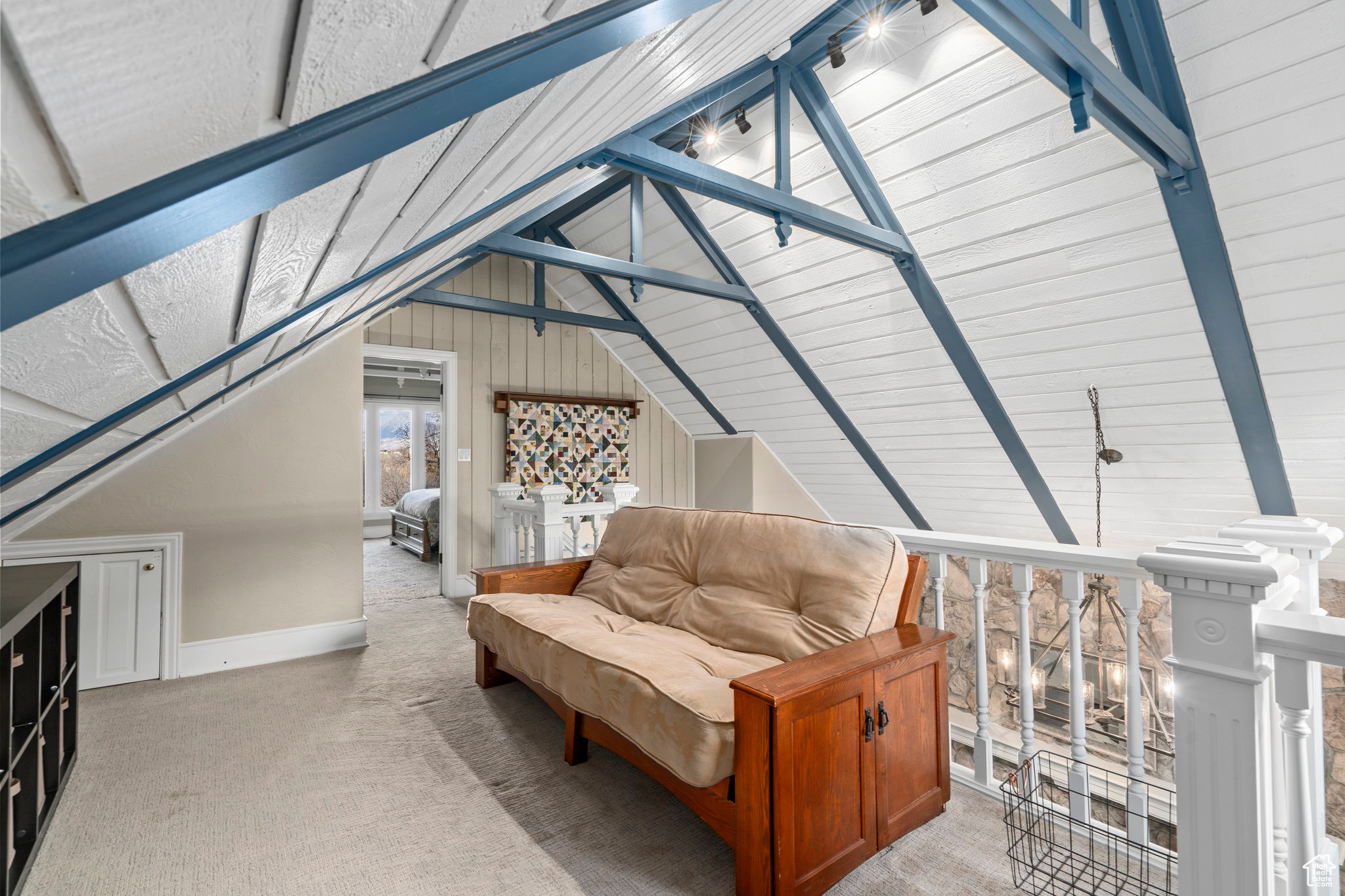 Additional living space with lofted ceiling, wooden walls, and carpet flooring overlooking the vaulted greatroom.