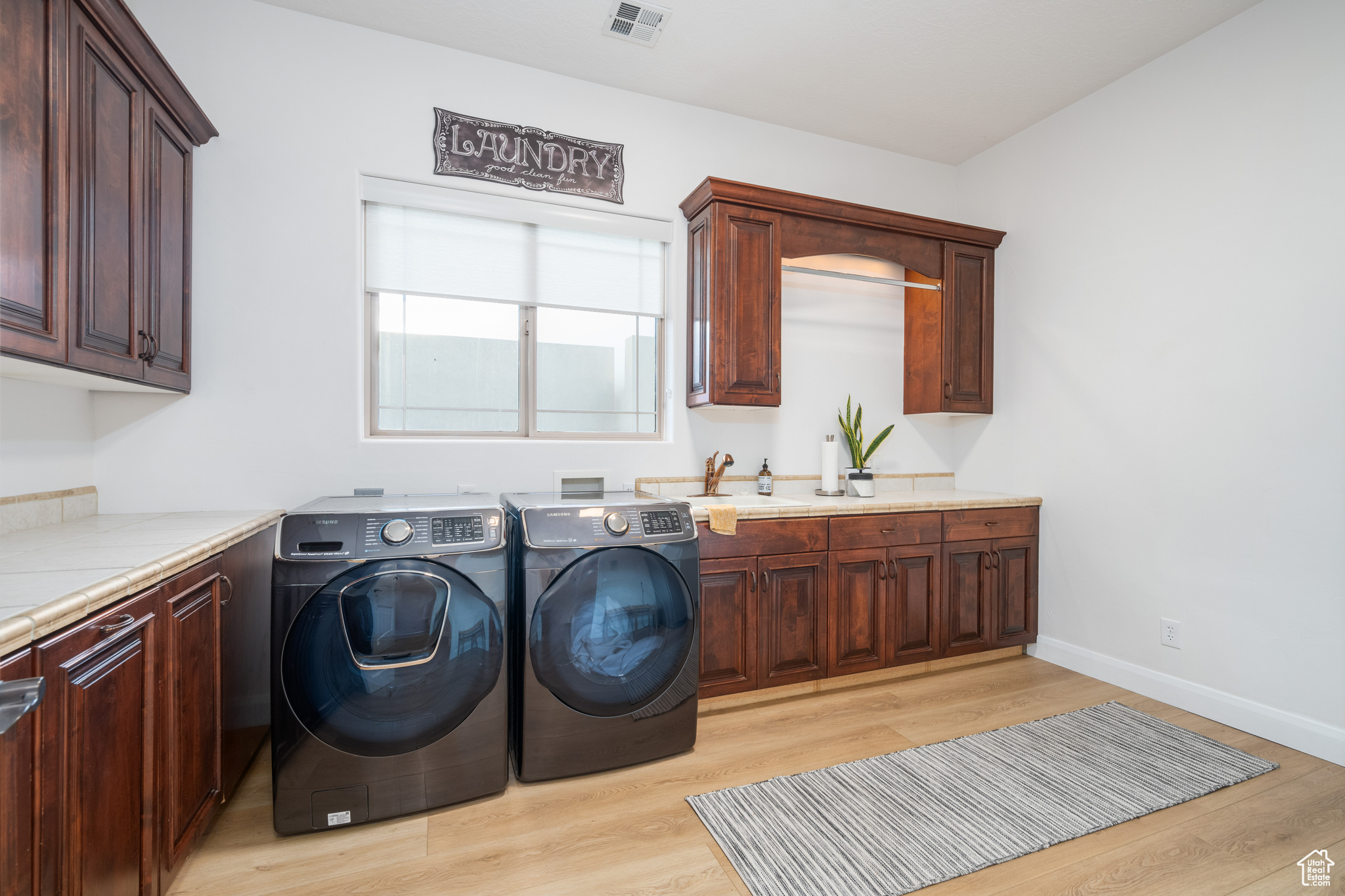 Washroom featuring light hardwood / wood-style flooring, cabinets, washer and dryer, and sink
