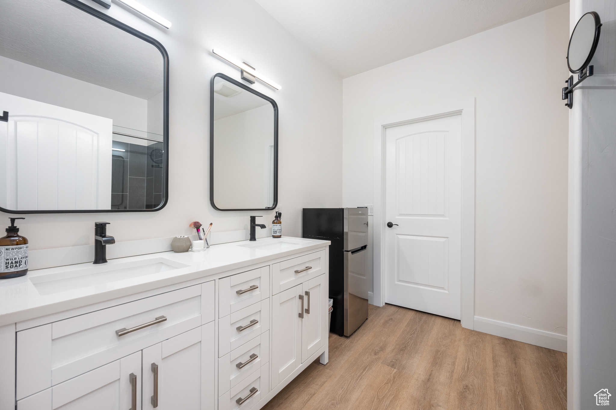 Bathroom featuring wood-type flooring, oversized vanity, and double sink