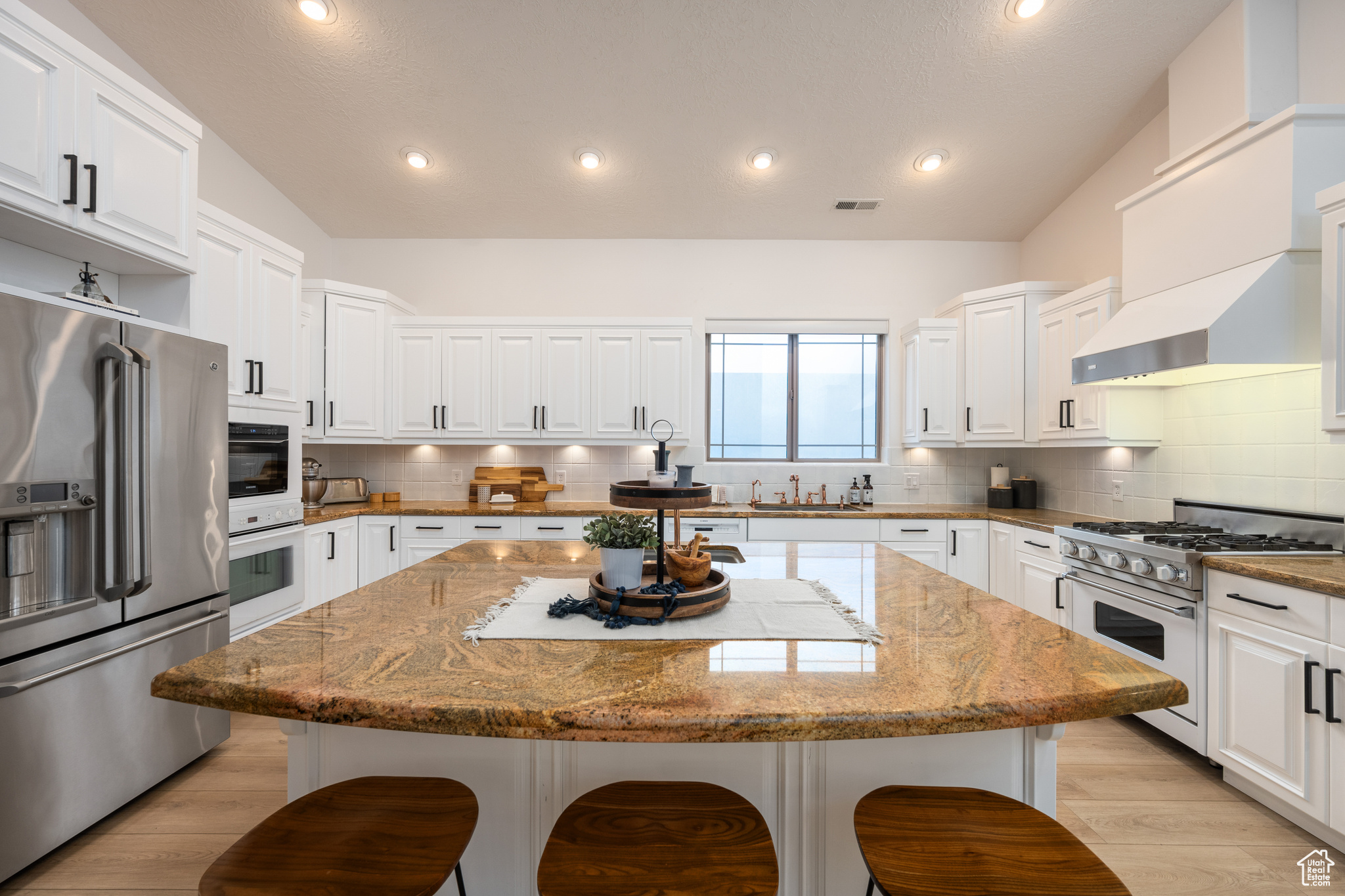 Kitchen featuring premium appliances, a center island, backsplash, and a breakfast bar area