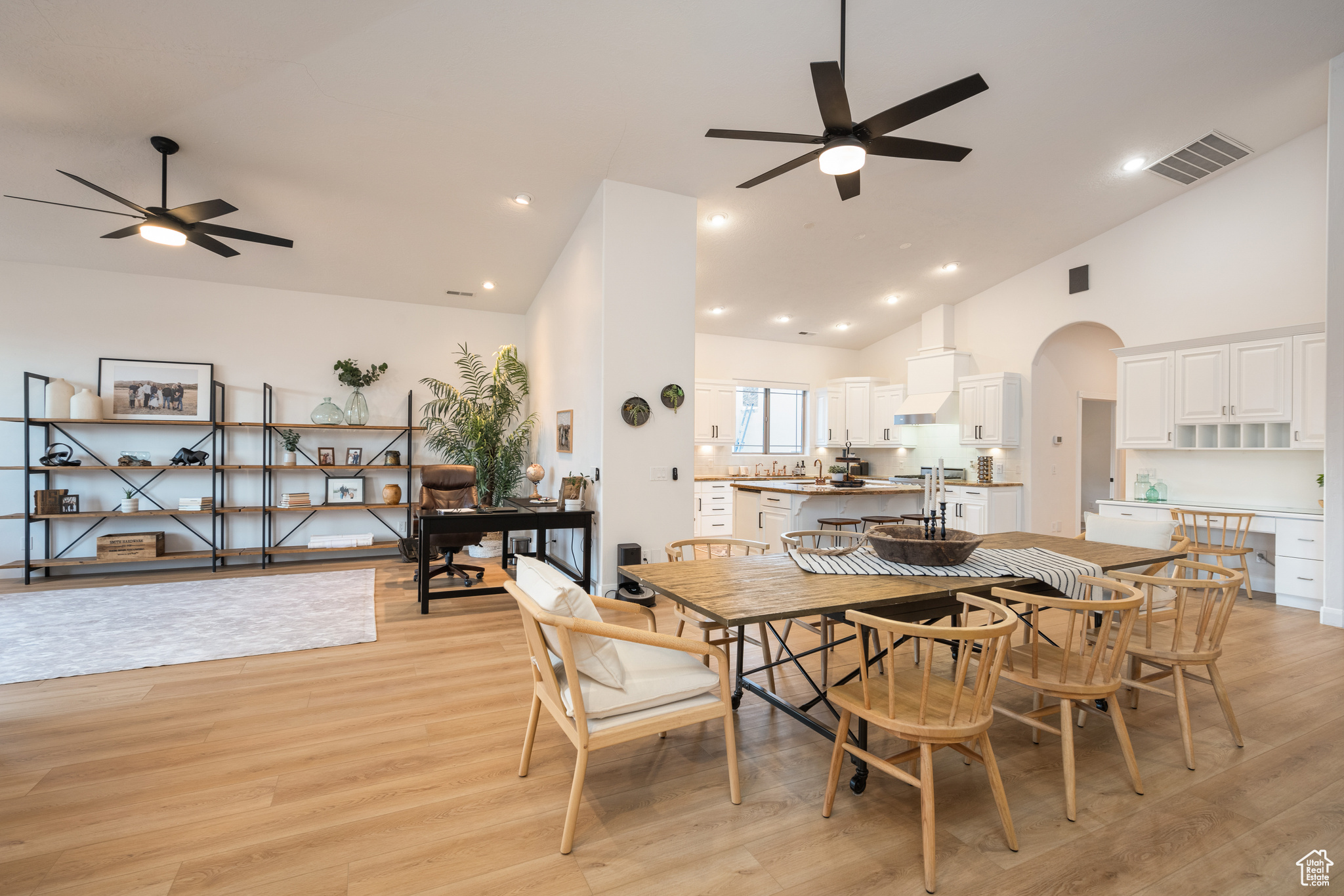 Dining space featuring light wood-type flooring, ceiling fan, and high vaulted ceiling