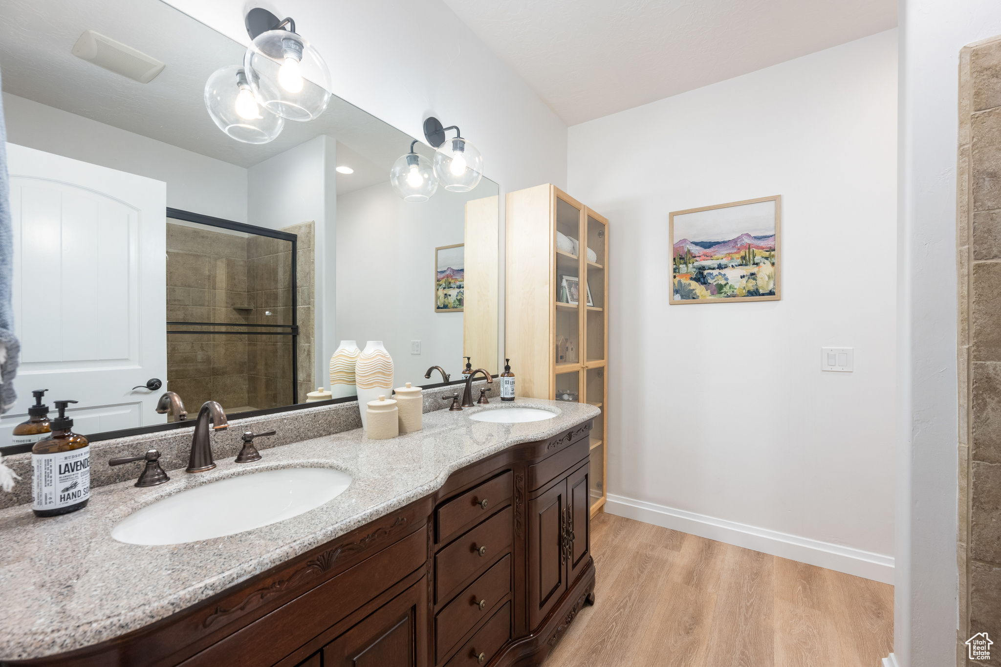 Bathroom with walk in shower, double sink, large vanity, and hardwood / wood-style floors
