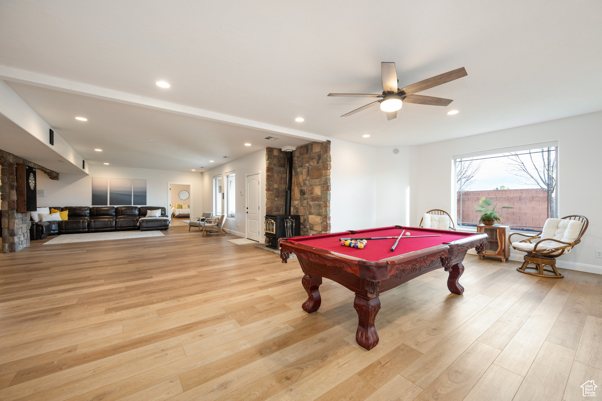 Recreation room featuring light hardwood / wood-style floors, pool table, ceiling fan, and a wood stove