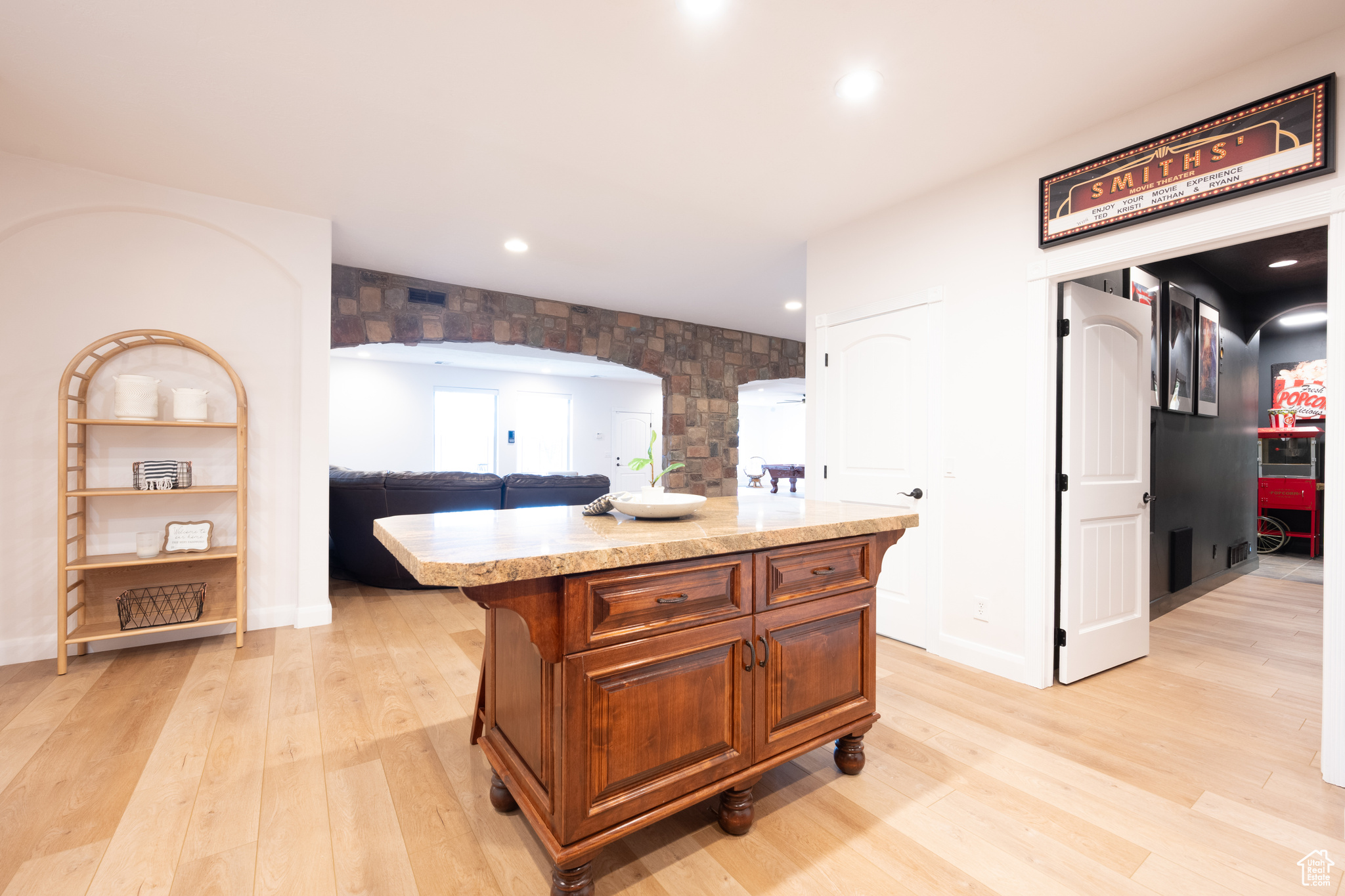 Kitchen featuring light wood-type flooring, light stone countertops, and a kitchen island