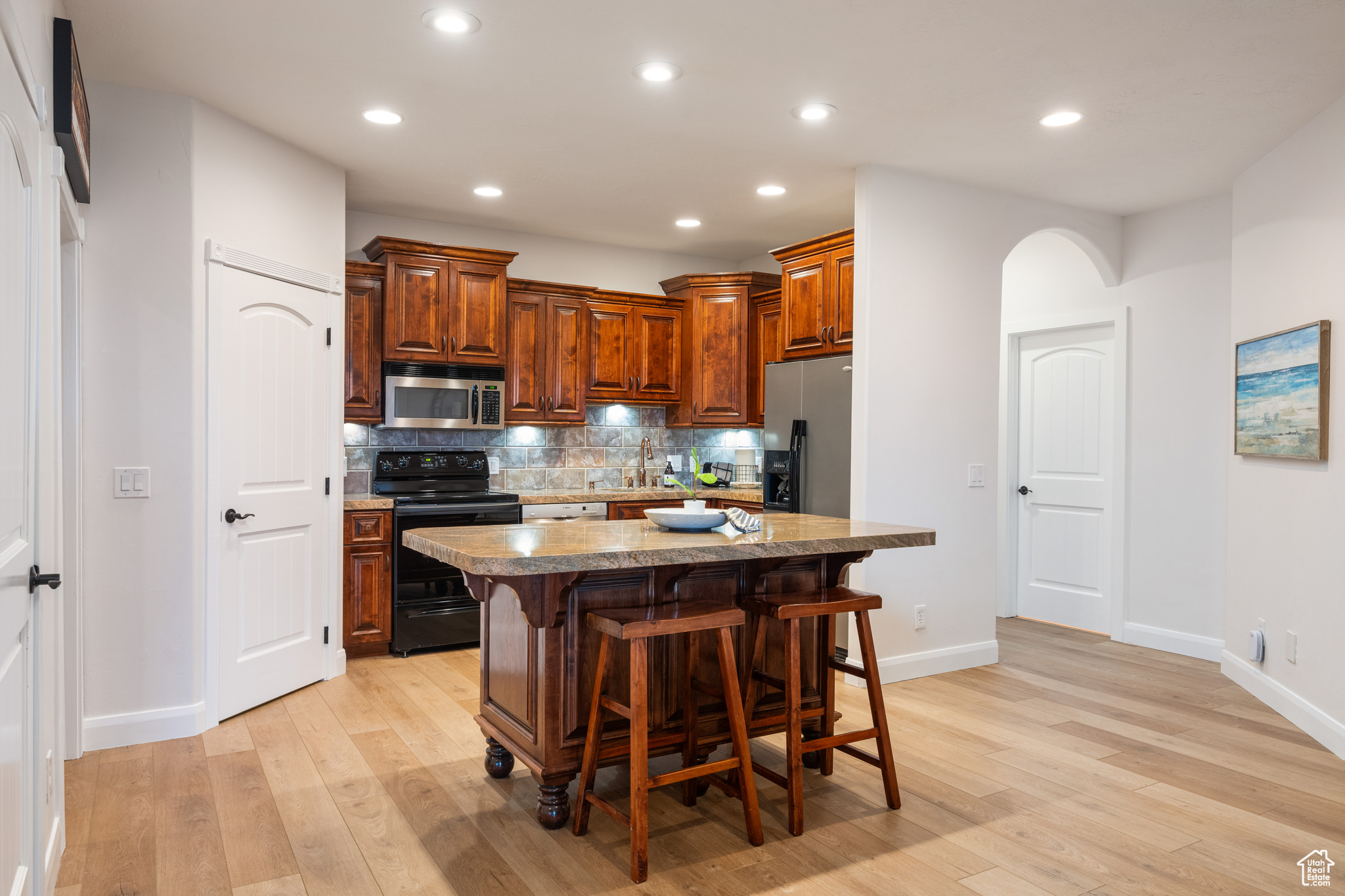 Kitchen featuring light hardwood / wood-style flooring, backsplash, a breakfast bar area, a center island, and stainless steel appliances