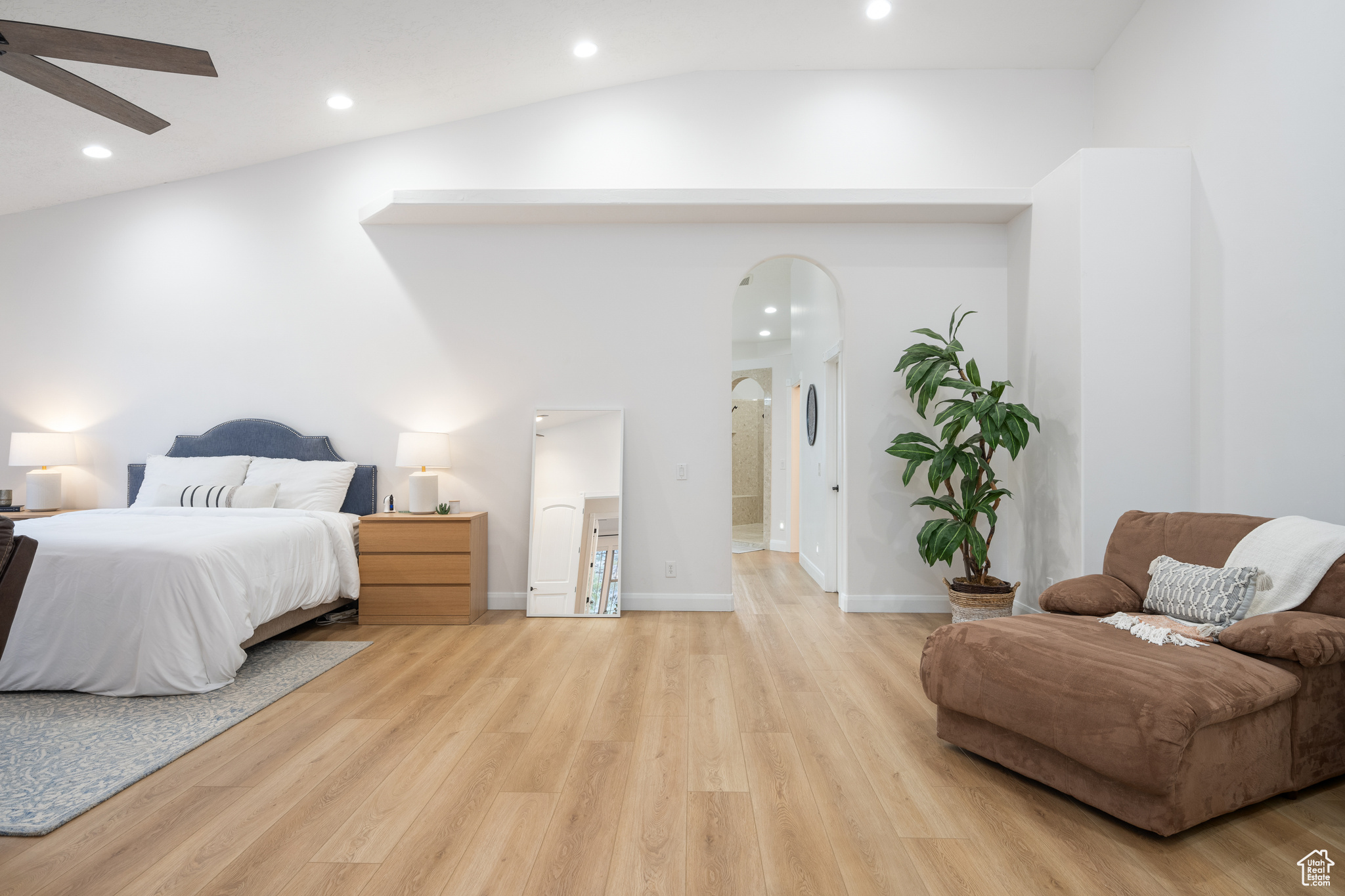 Bedroom featuring light hardwood / wood-style floors, lofted ceiling, ceiling fan, and connected bathroom