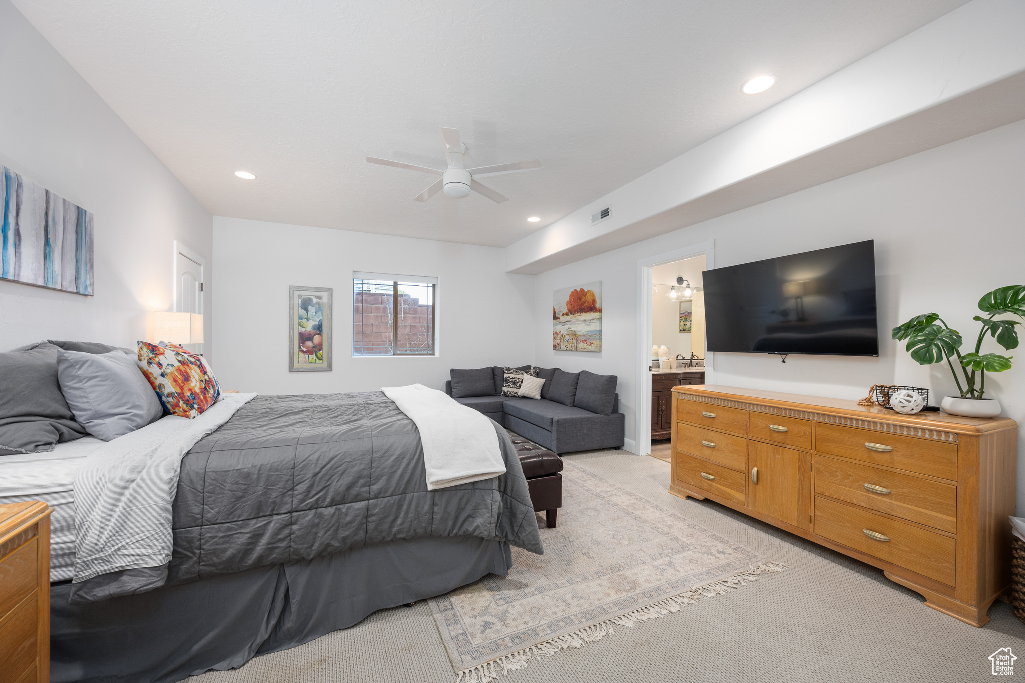 Carpeted bedroom with ceiling fan and connected bathroom