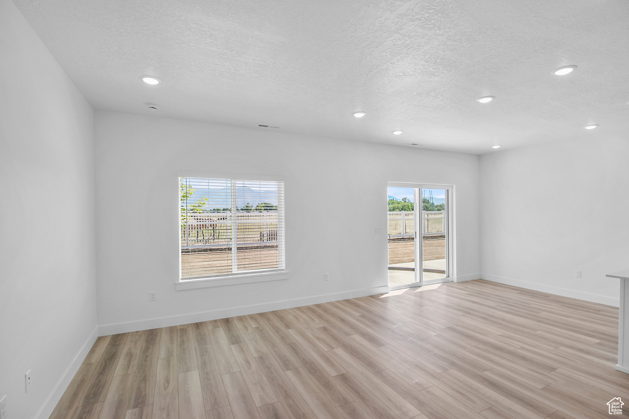 Living and Dining rooms featuring light wood-type flooring and a sliding door to semi private patio.
