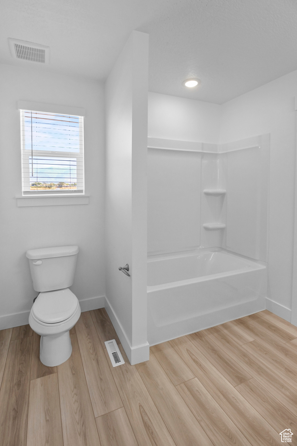 Bathroom featuring bathtub / shower combination, toilet, and hardwood / wood-style flooring