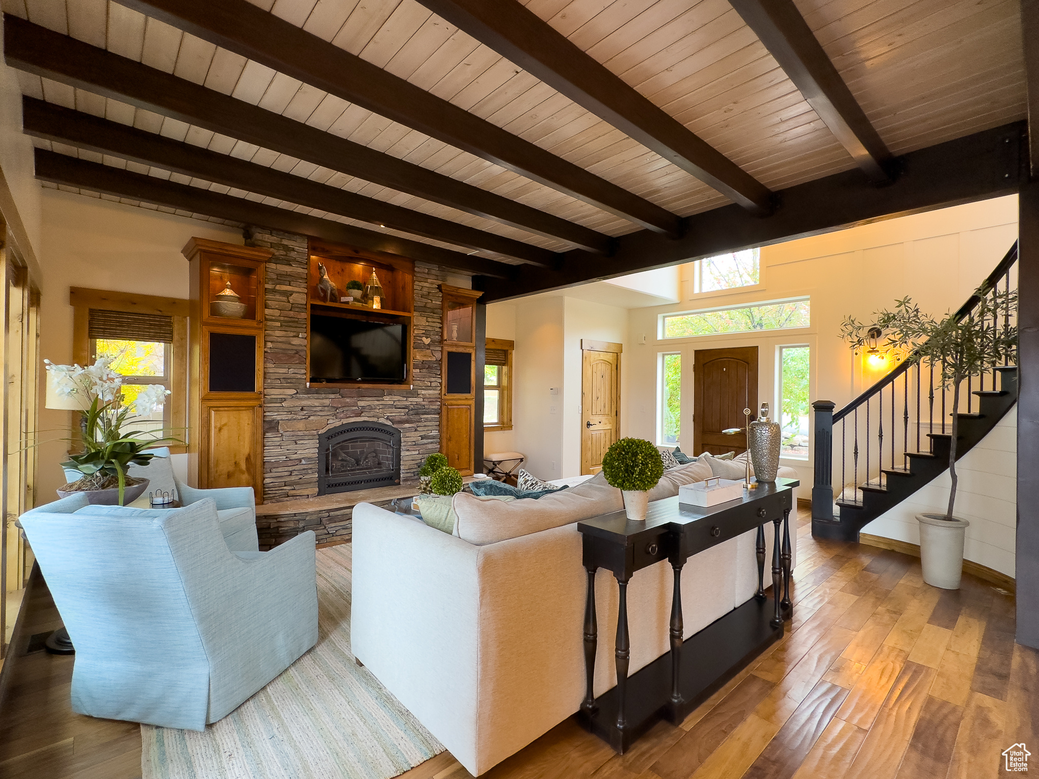 Living room featuring a stone fireplace, wood ceiling, beam ceiling, and hardwood / wood-style flooring