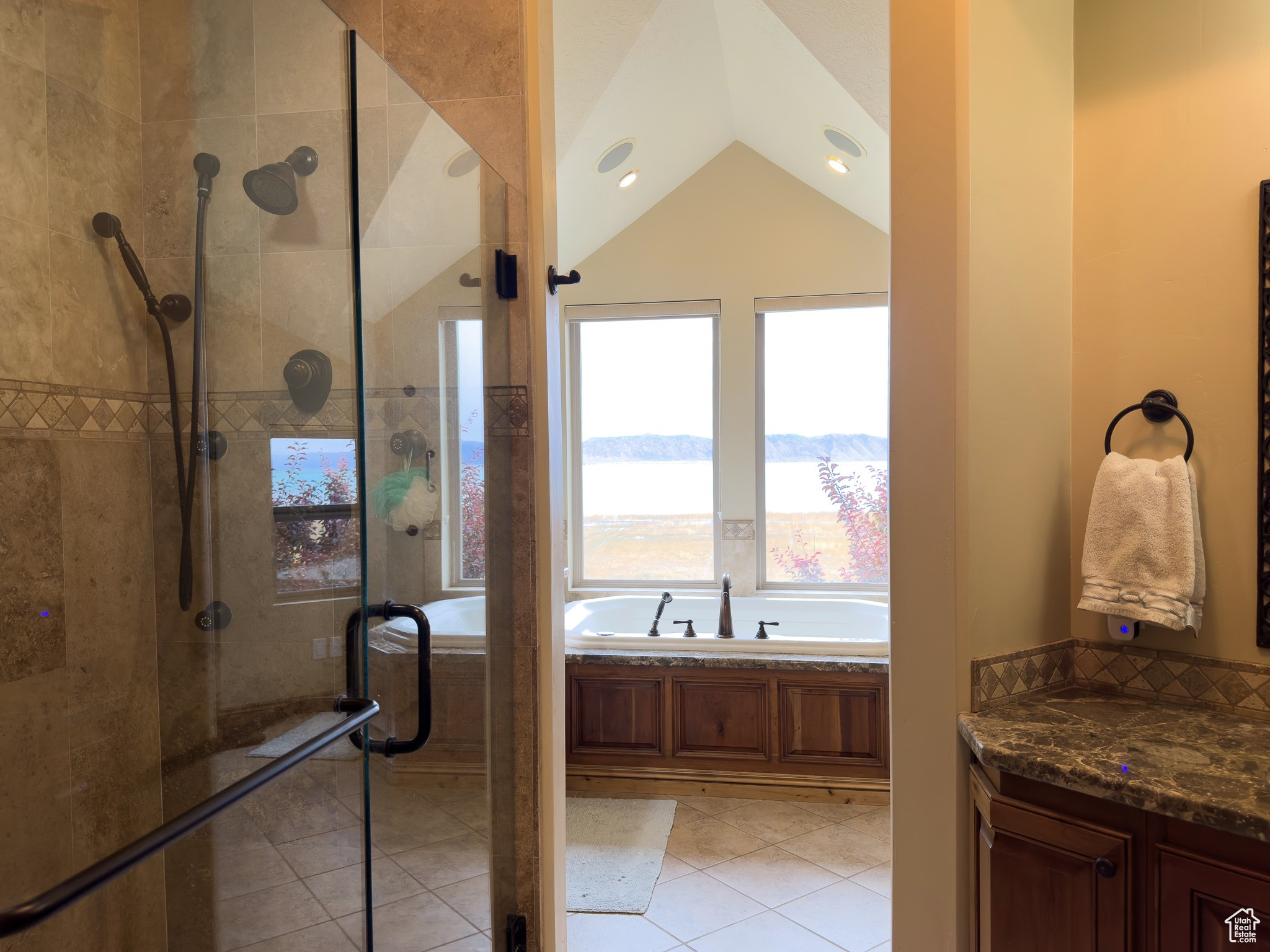 Bathroom featuring tile floors, vaulted ceiling, and plus walk in shower