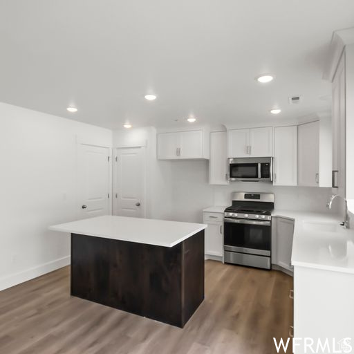 Kitchen featuring dark hardwood / wood-style floors, appliances with stainless steel finishes, white cabinets, and sink