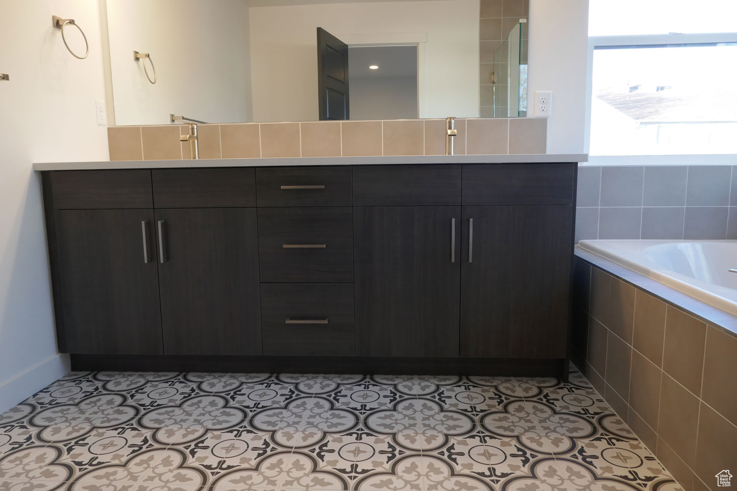 Primary Bathroom with tile flooring, a relaxing tiled bath, and vanity