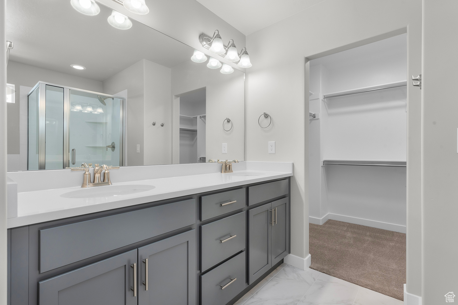 Bathroom featuring vanity with extensive cabinet space, an enclosed shower, dual sinks, and tile flooring