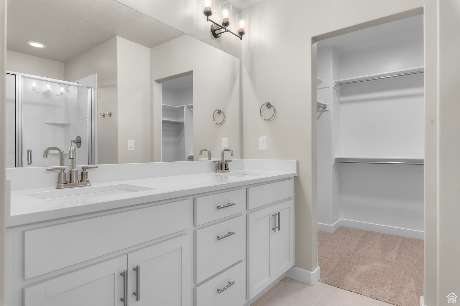 Bathroom featuring walk in shower, oversized vanity, double sink, and tile floors
