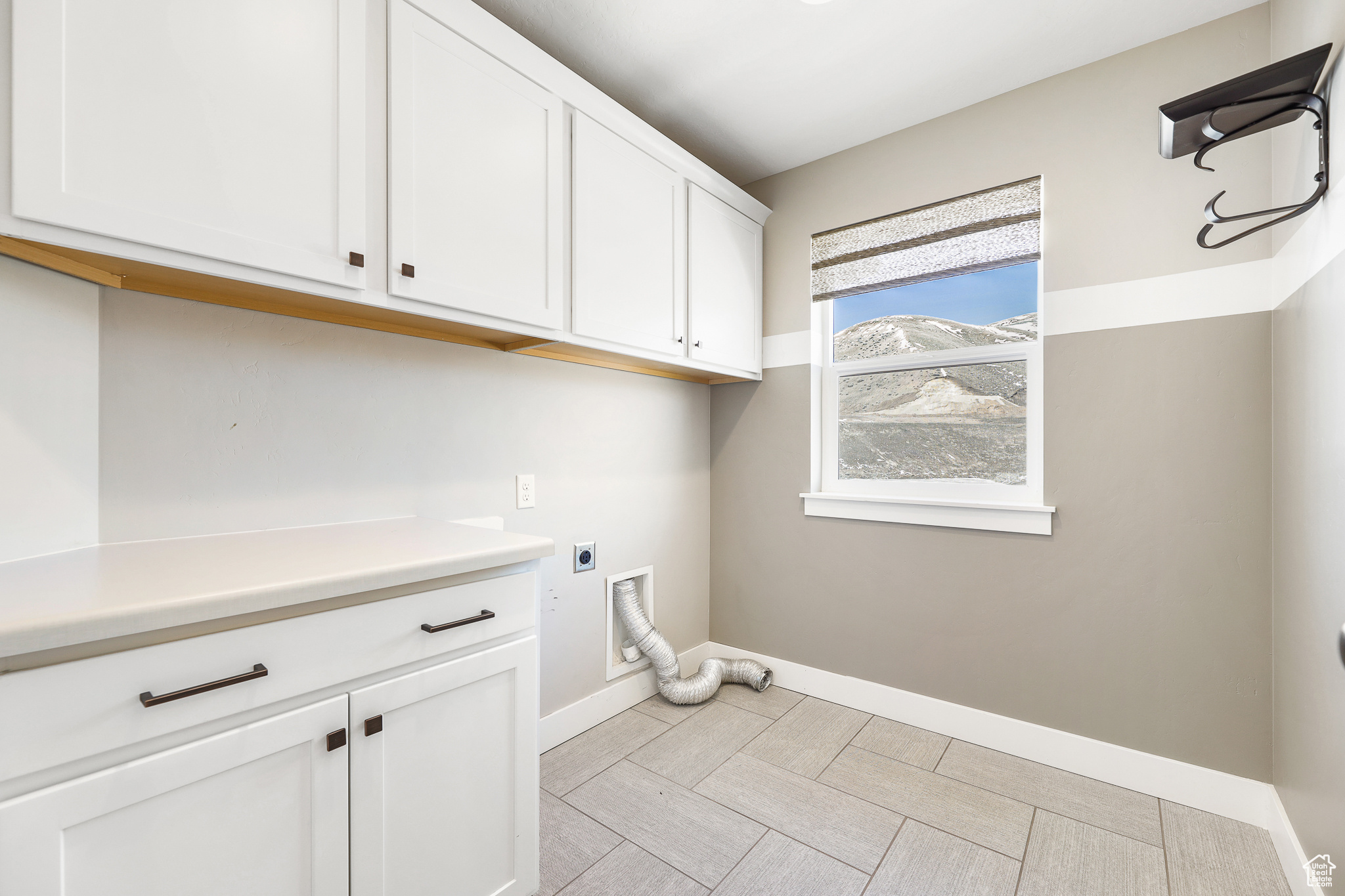 Laundry room featuring hookup for an electric dryer, light tile floors, and cabinets