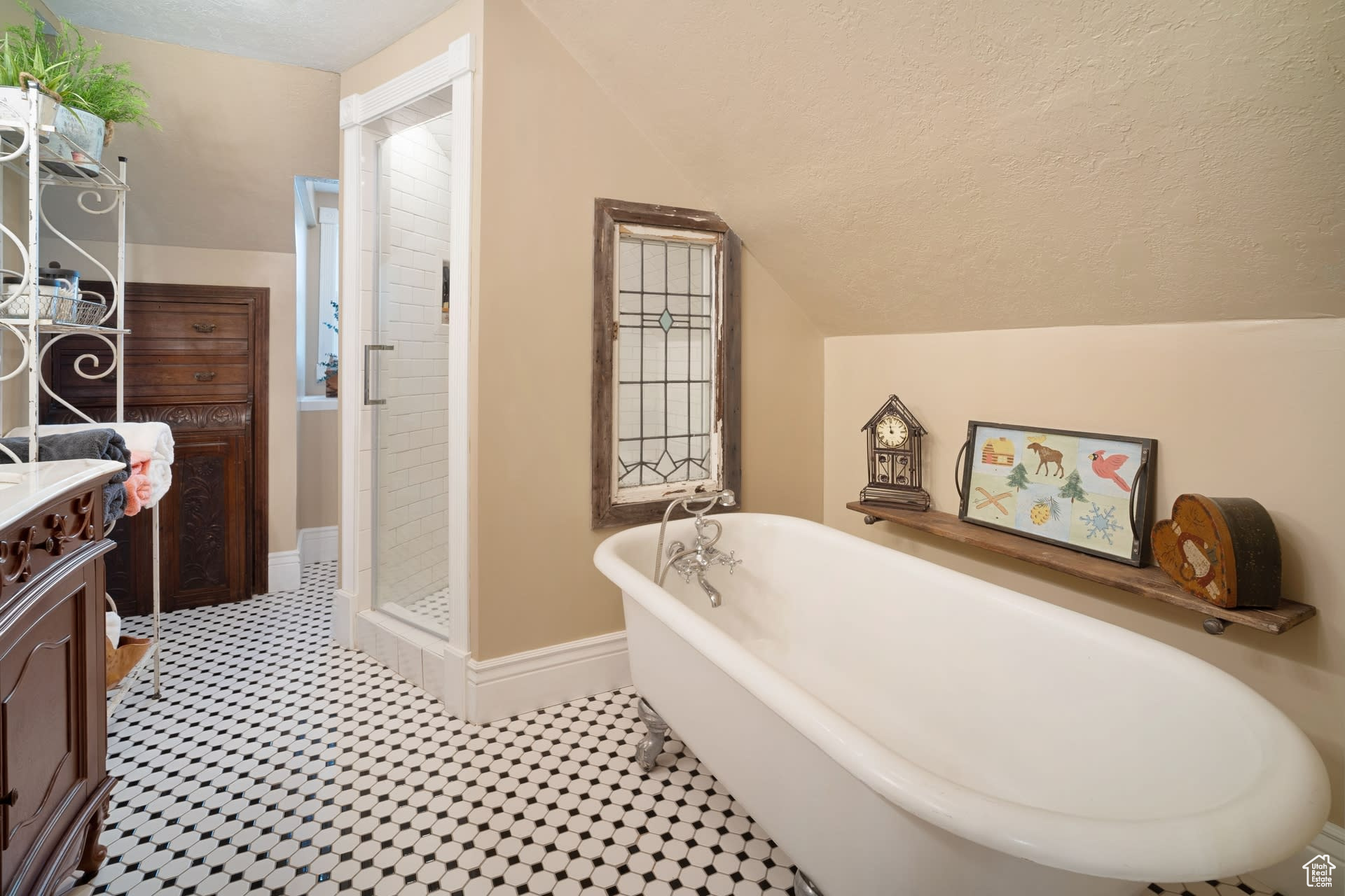 Bathroom featuring vanity, vaulted ceiling, a washtub, and a textured ceiling